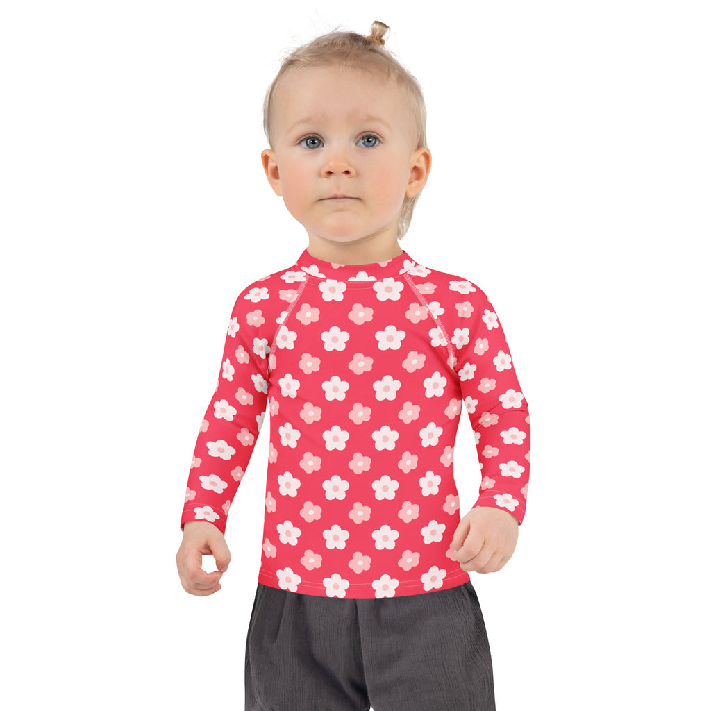 A girl wearing a vibrant pink long sleeve rash guard with white and light pink flowers and UPF 50+ protection
