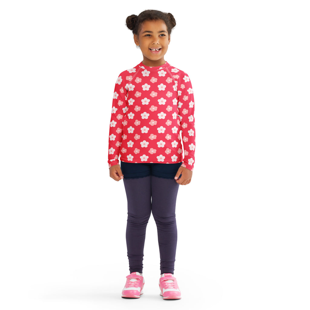A vibrant pink girls long sleeve rash guard swim shirt with white and light peach floral pattern and UPF 50 plus protection