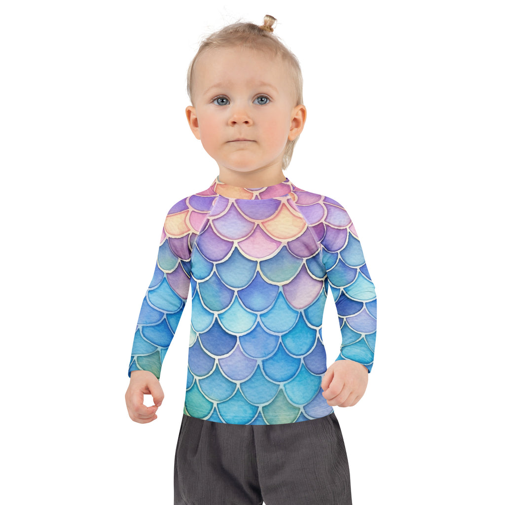 A child wearing a girls watercolor rainbow mermaid long sleeve rash guard swim shirt in purple blue and teal with upf 50+