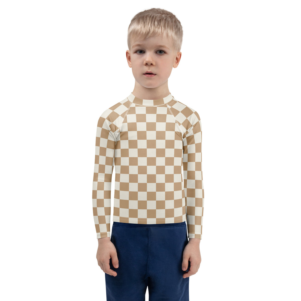 A child wearing a beige and white checkered kids sand checkerboard long sleeve rash guard with UPF 50+ protection