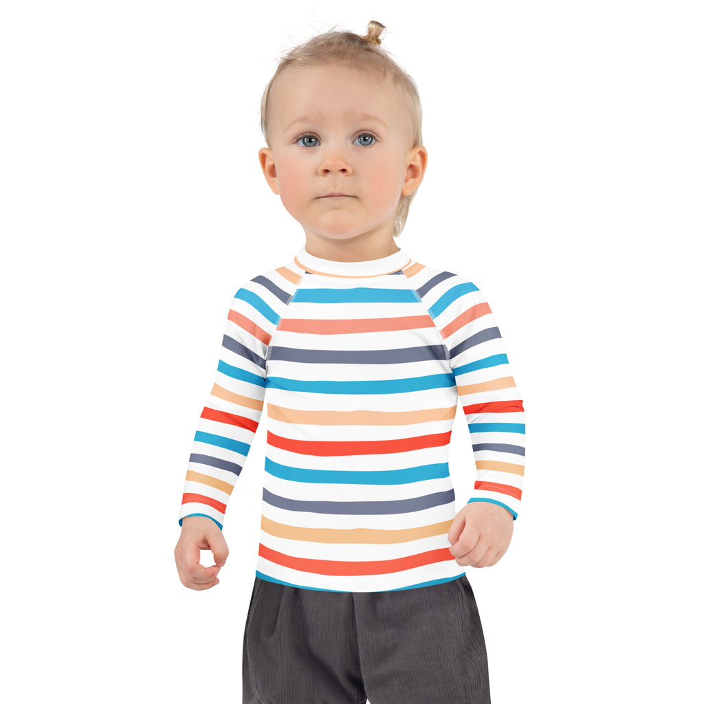A child wearing a kids coastal stripes long sleeve rash guard swim shirt with colorful stripes and UPF 50 plus protection