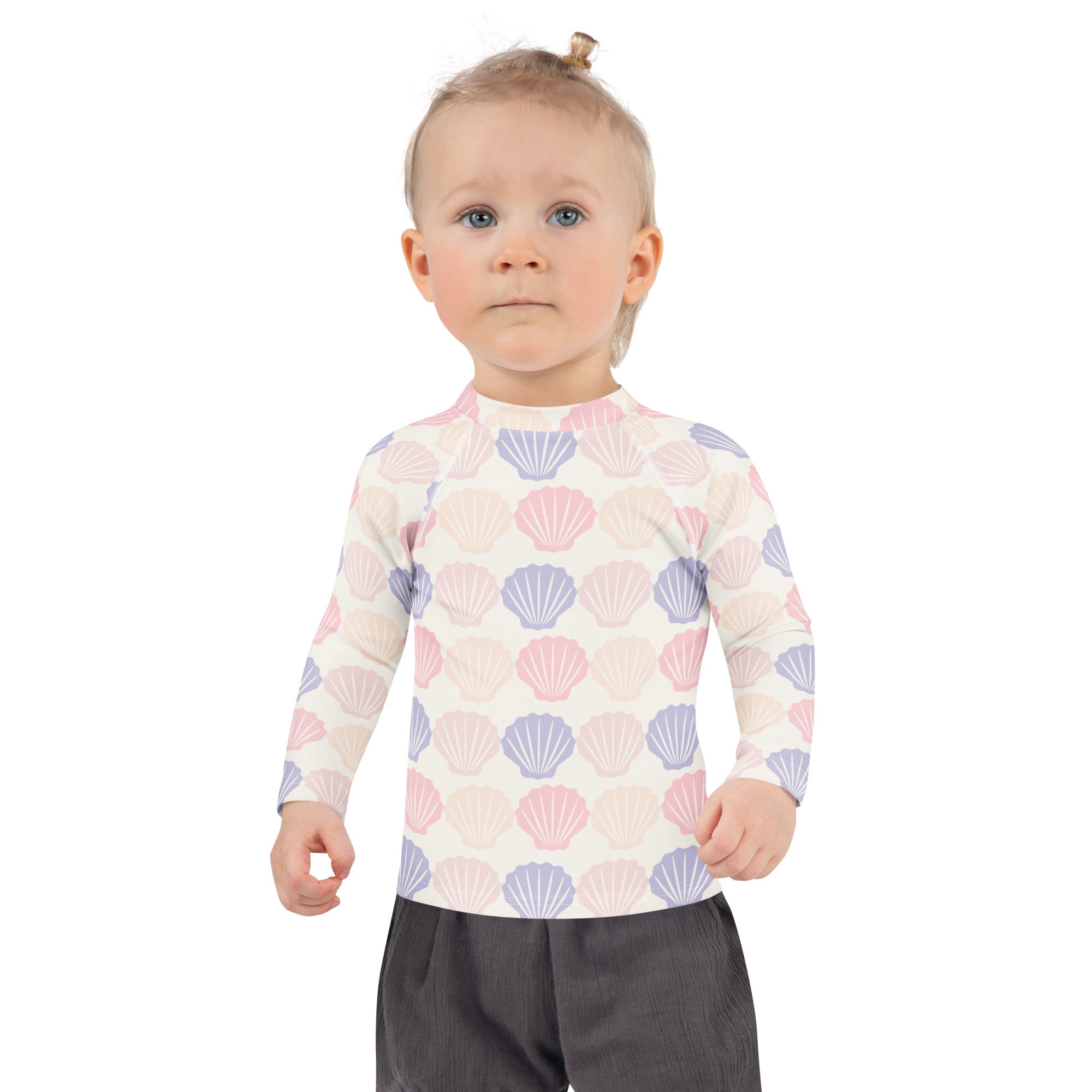 A child wearing a kids seashell print long sleeve rash guard swim shirt with upf 50 plus in pastel pink and lavender