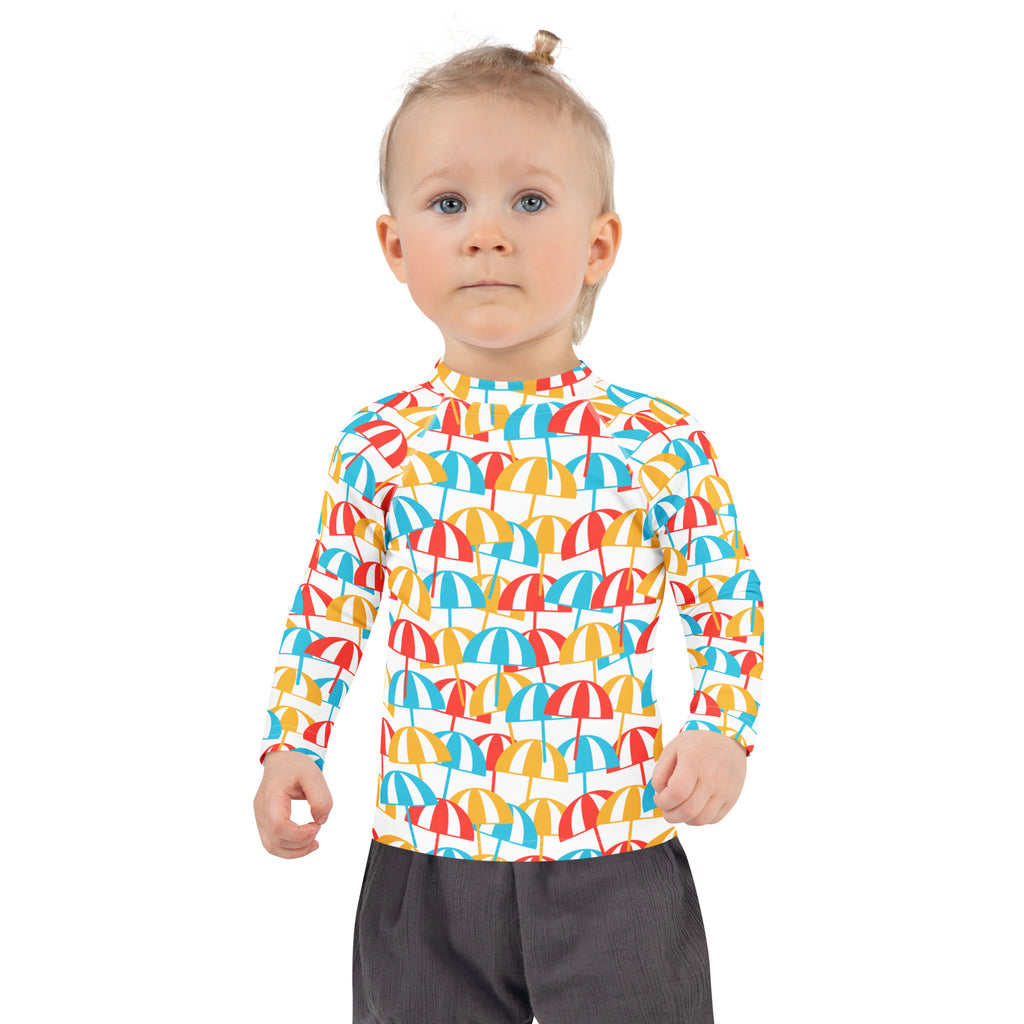 A child wearing a white kids beach umbrella long sleeve rash guard with colorful umbrella pattern and UPF 50+ protection