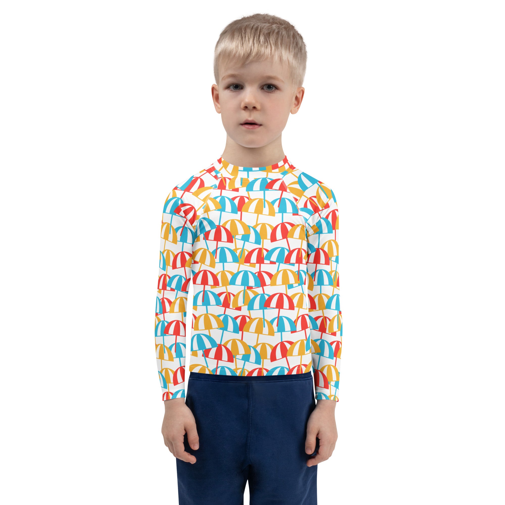 A child wearing a kids beach umbrella long sleeve rash guard with vibrant red yellow and blue umbrella pattern and UPF 50+