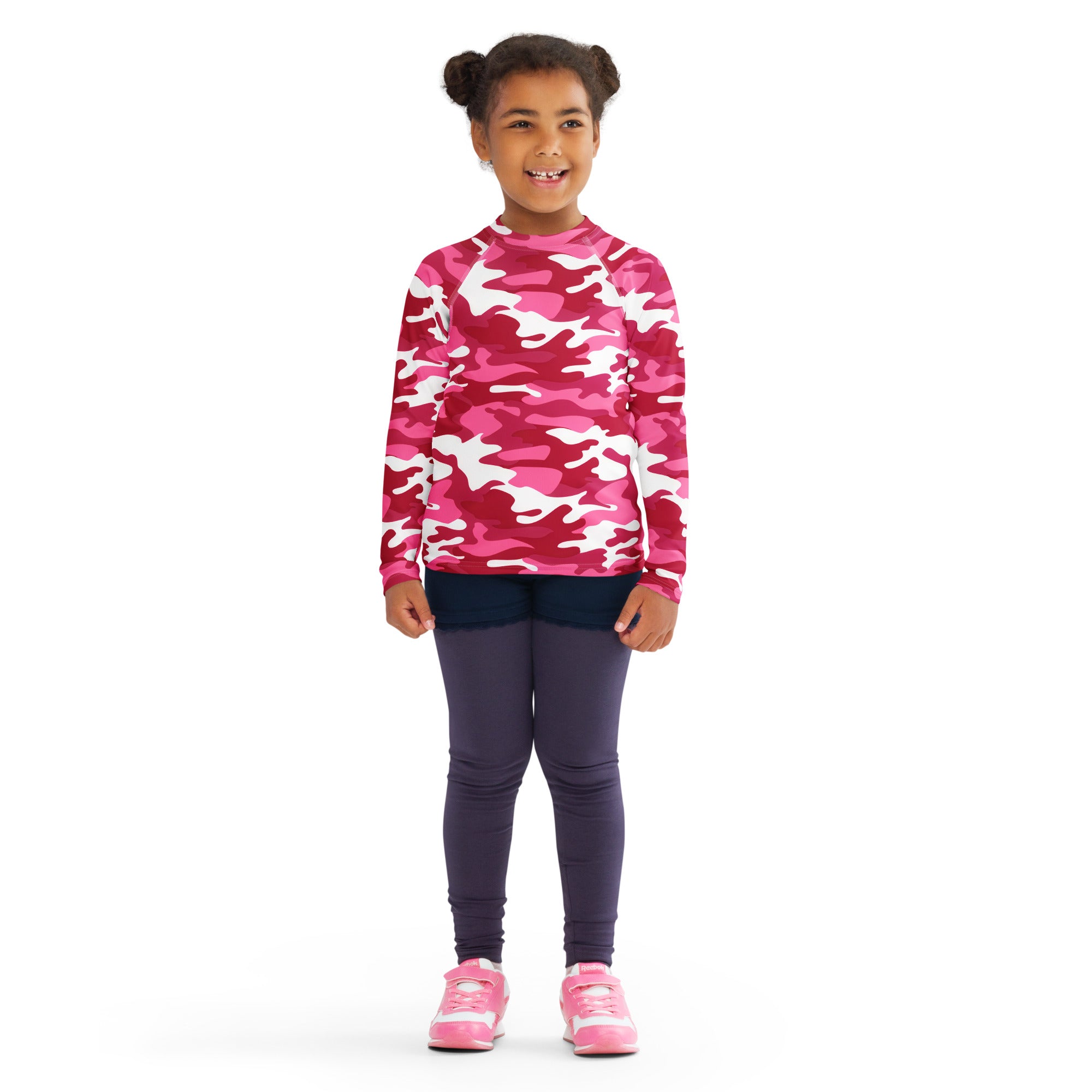 A girl wearing a girls pink camouflage long sleeve rash guard swim shirt with upf 50 plus for sun protection