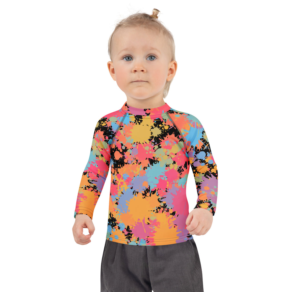 A child wearing a kids paint splatter long sleeve rash guard swim shirt with vibrant colors and UPF 50+ protection