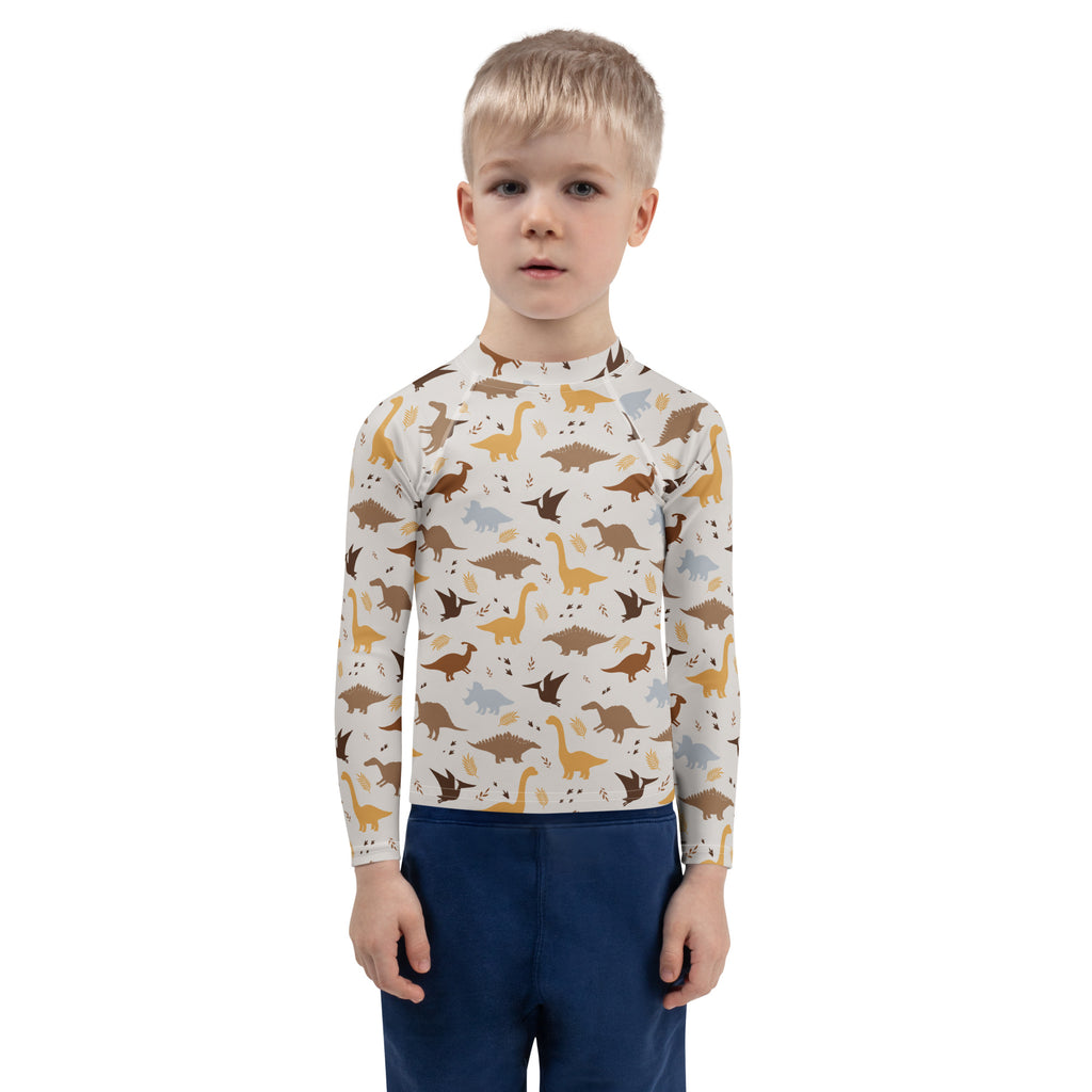 Kids dinosaur long sleeve rash guard swim shirt with upf 50 plus featuring brown tan and gray dinosaurs on off white background