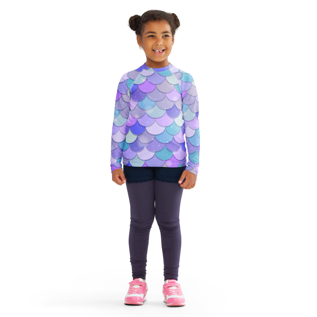 A child wearing a girls purple mermaid scales long sleeve rash guard swim shirt with UPF 50 plus protection