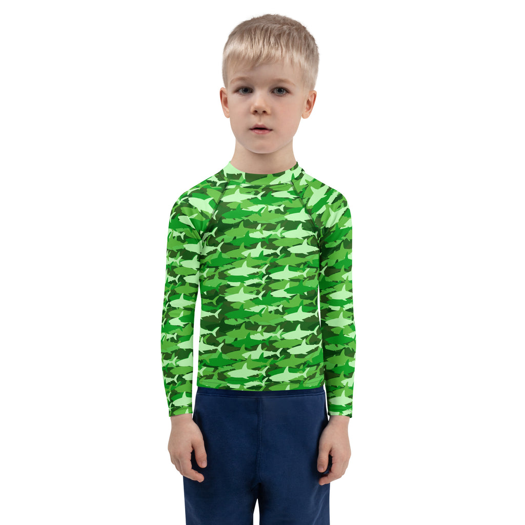 A child wearing a kids green shark long sleeve rash guard swim shirt with UPF 50 plus for sun protection