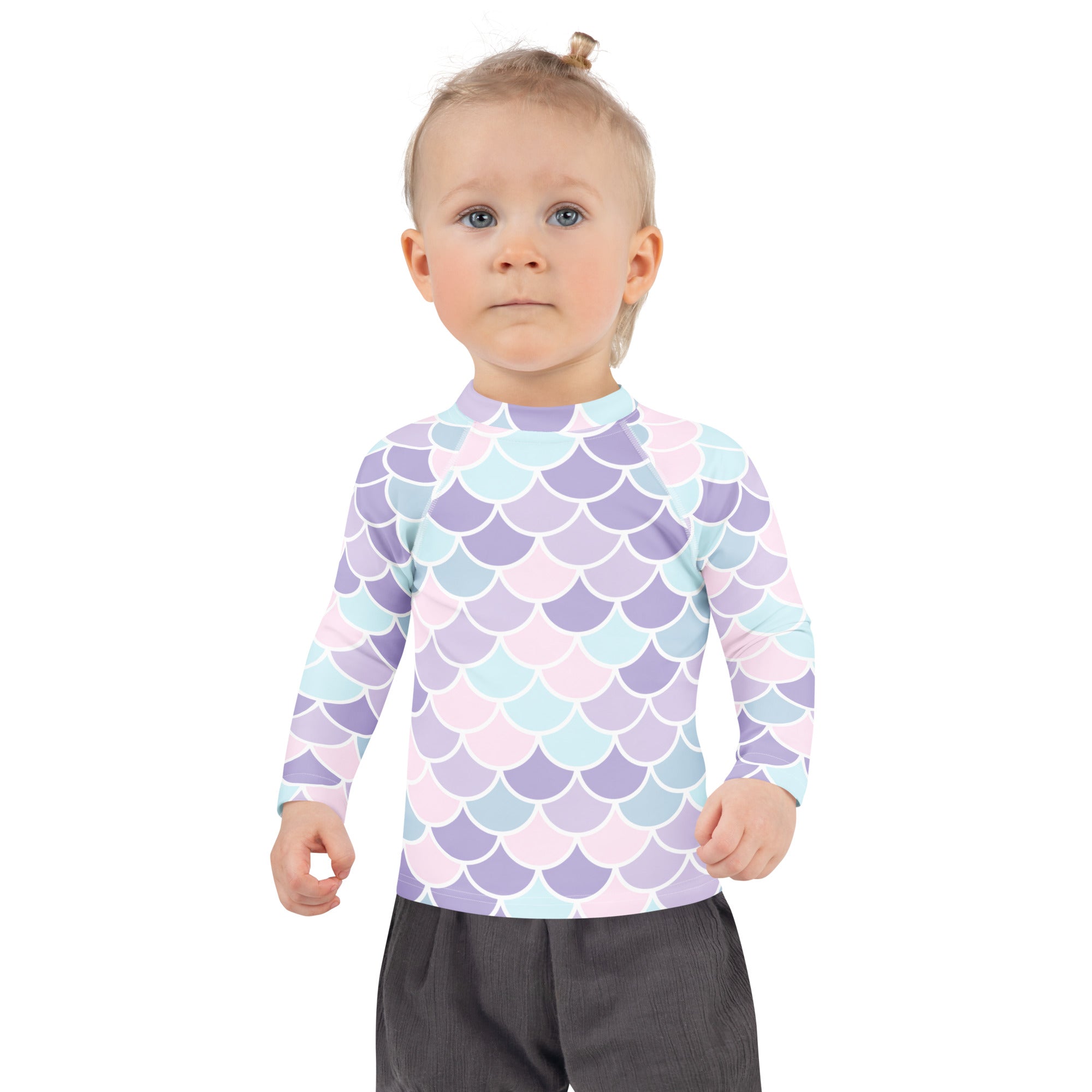 A child wearing a girls mermaid scale long sleeve rash guard swim shirt with upf 50 plus in pastel lavender blue and pink