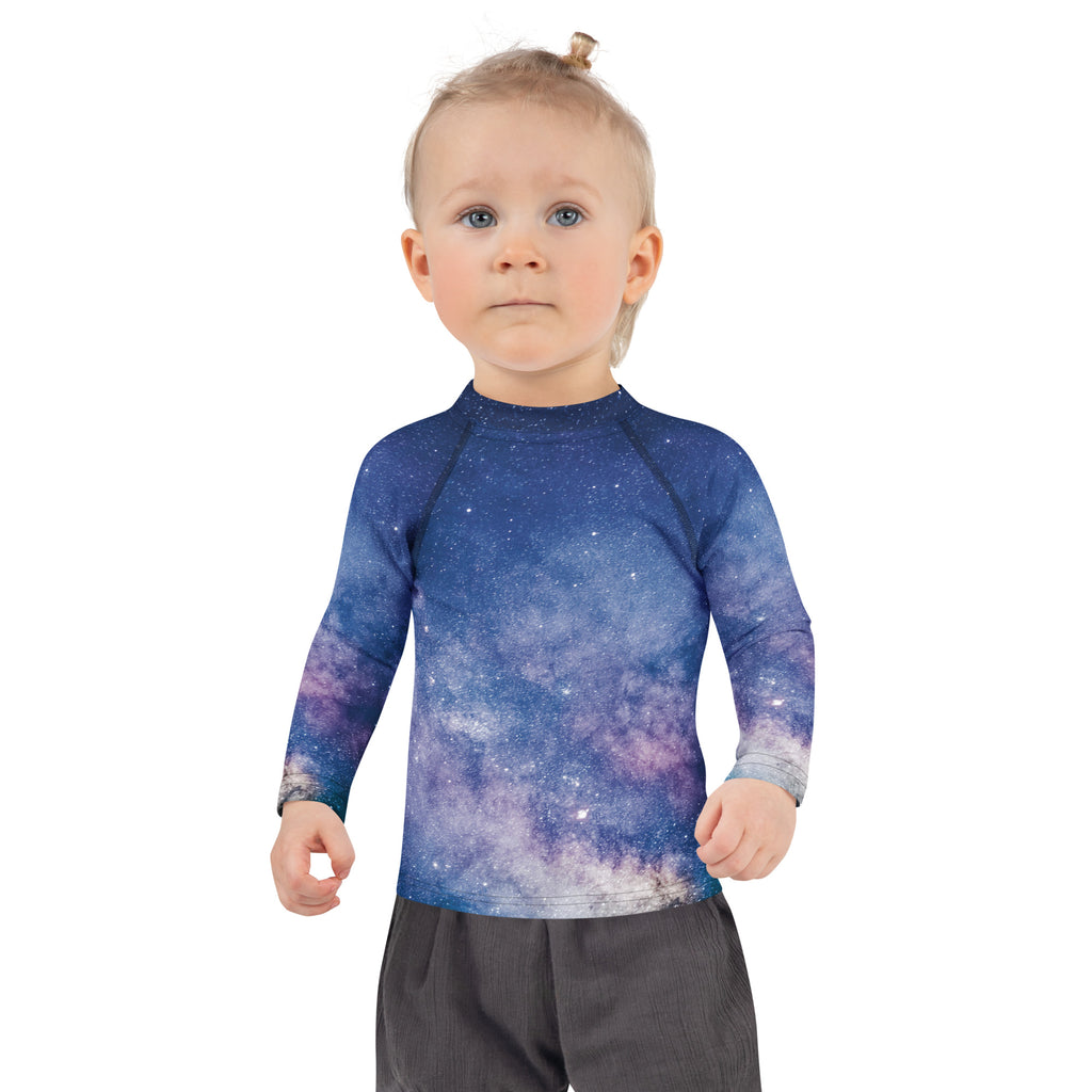 A child wearing a kids realistic galaxy long sleeve rash guard swim shirt with vibrant blue and purple galaxy print and UPF 50+ protection