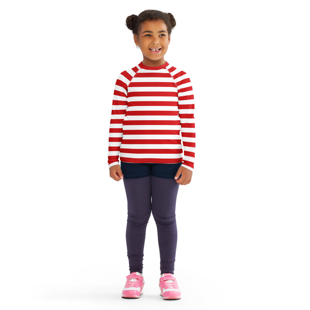 A child wearing a kids red and white striped long sleeve rash guard swim shirt with UPF 50+ and dark leggings