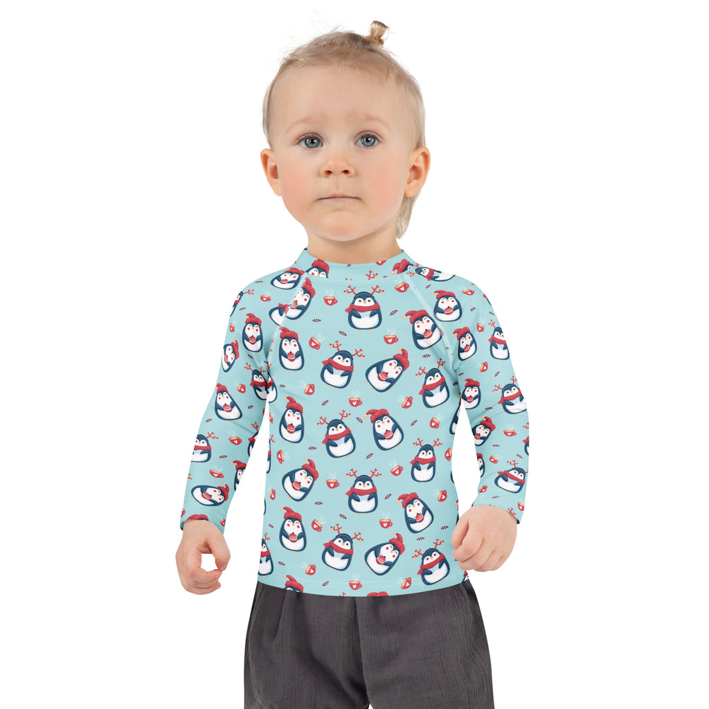 A child wearing a light blue kids reindeer penguin christmas long sleeve rash guard swim shirt with upf 50+ and penguin pattern