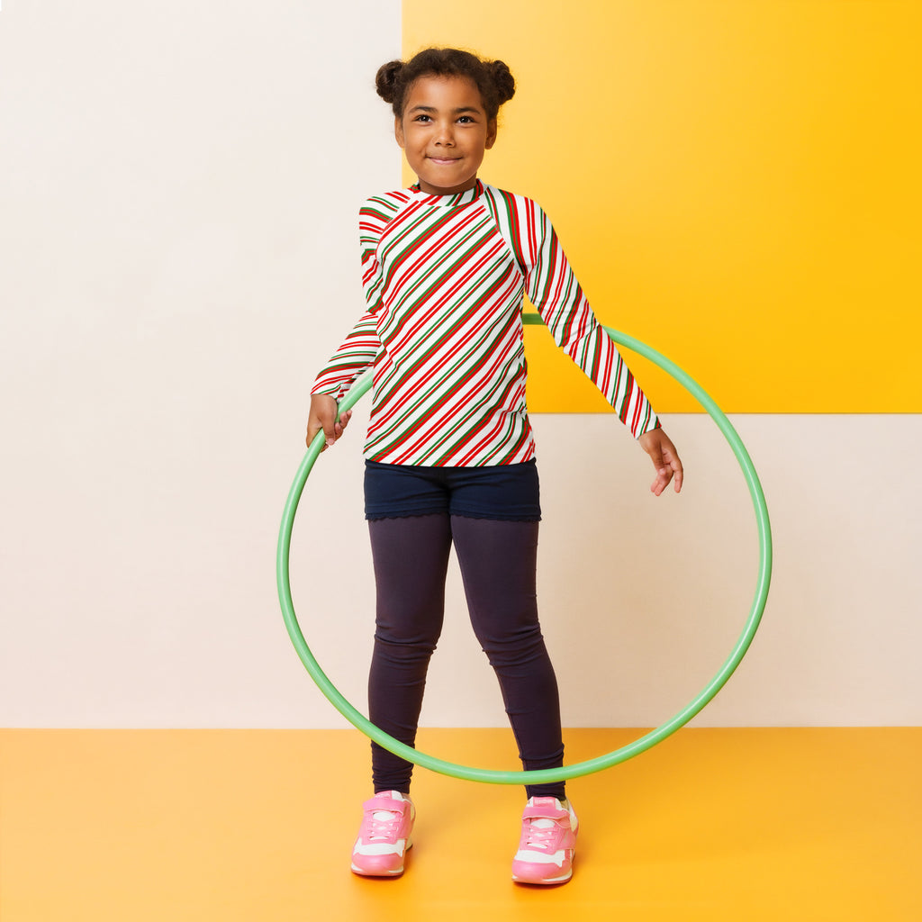 Green plastic hula hoop beside kids candy cane stripe christmas long sleeve rash guard swim shirt with upf 50 plus