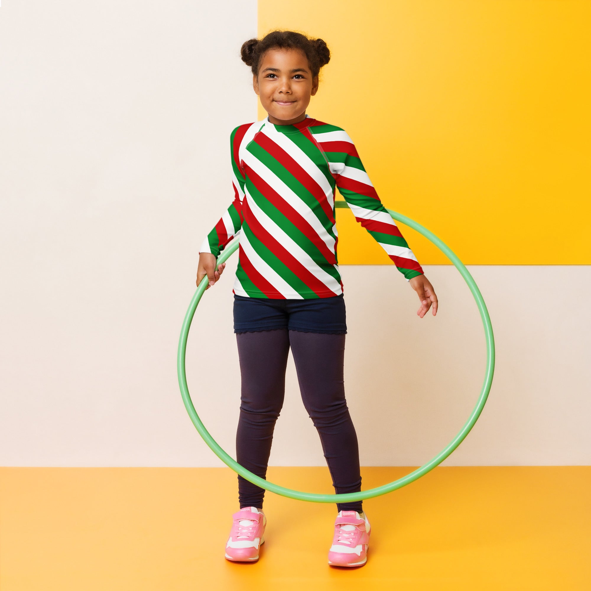 Green plastic hula hoop paired with kids bold candy cane stripe christmas long sleeve rash guard swim shirt with UPF 50+