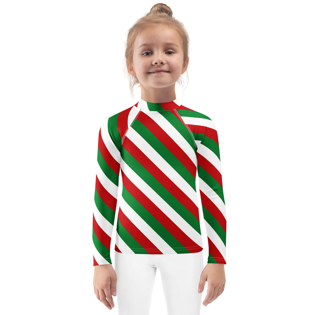 A child wearing a kids bold candy cane stripe christmas long sleeve rash guard swim shirt with upf 50+ in red green and white