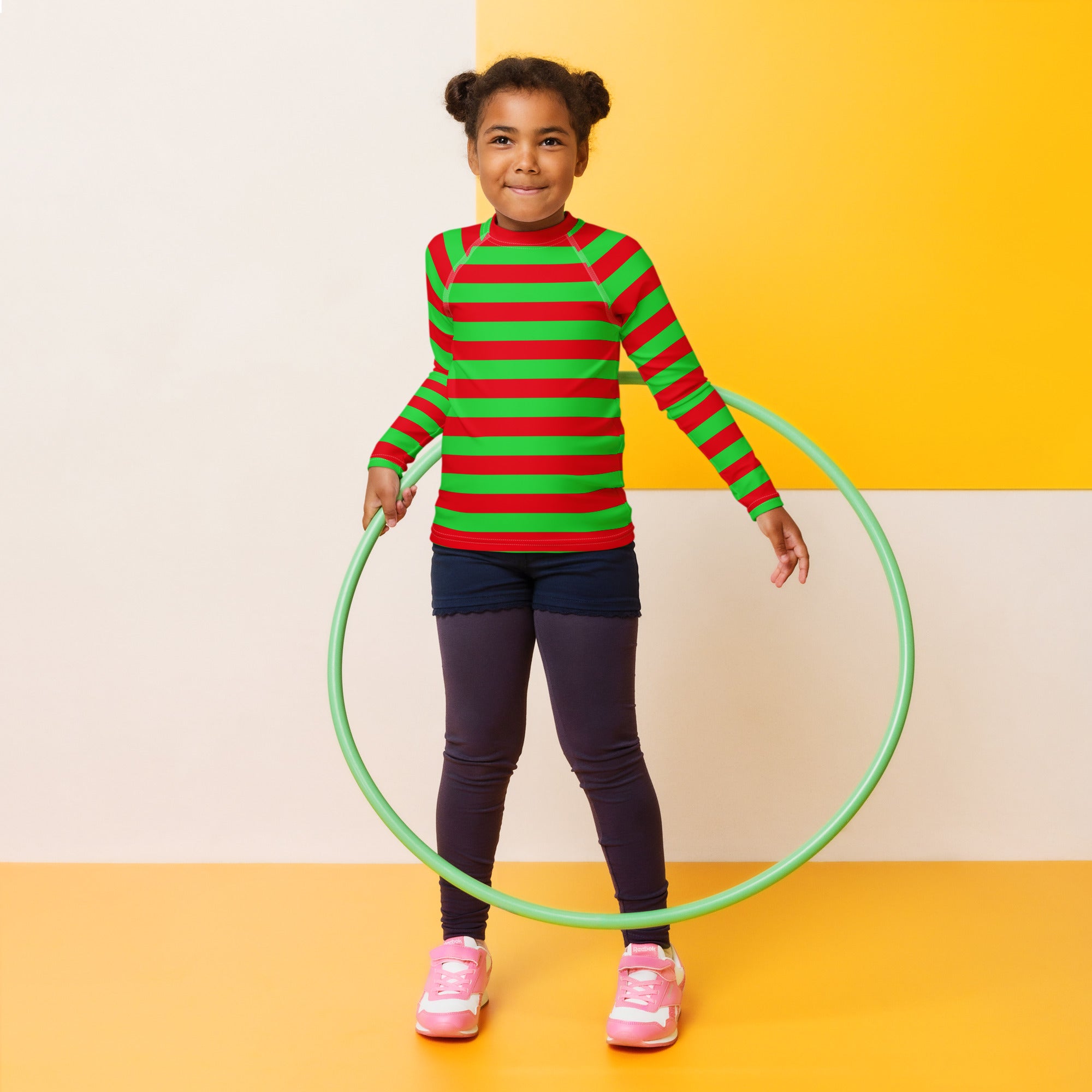 Light green plastic hula hoop displayed alongside kids red and green striped christmas long sleeve rash guard with upf 50+