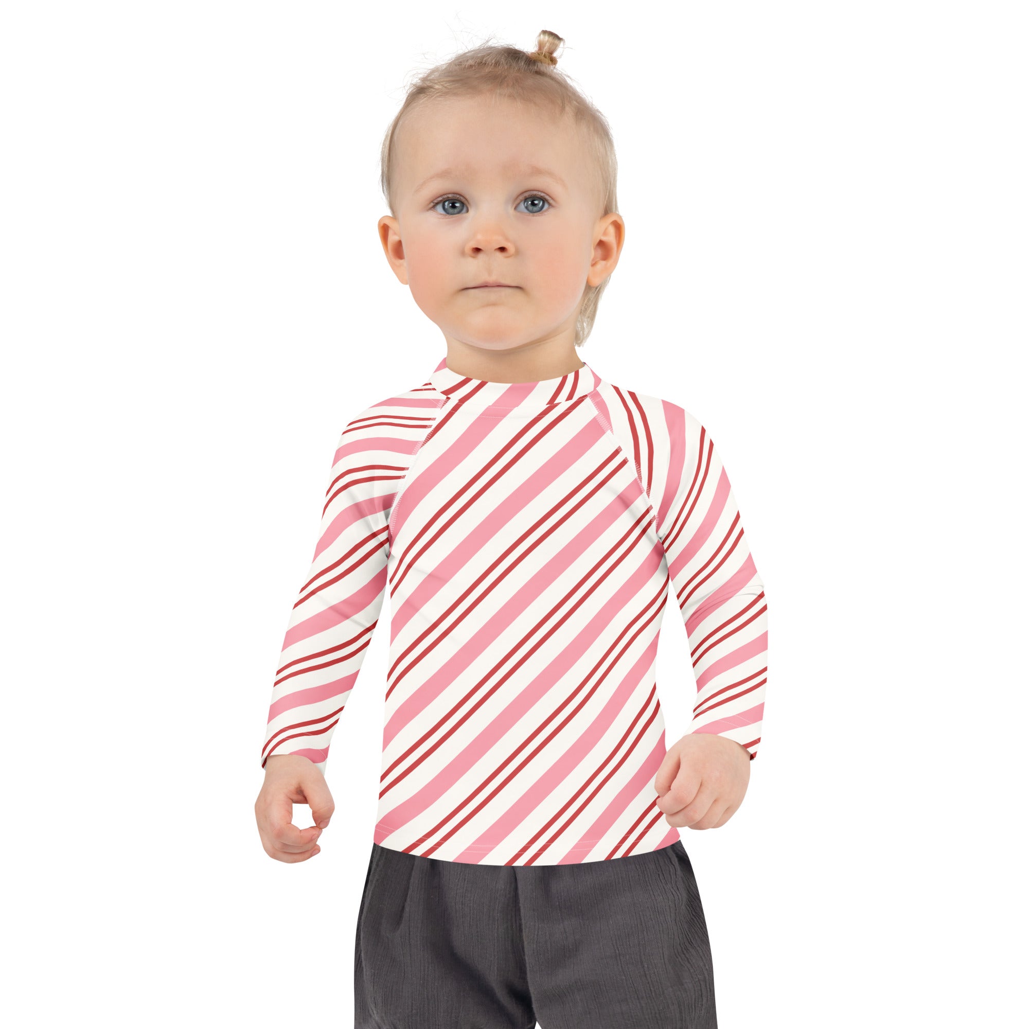 A child wearing a kids pink peppermint stripe Christmas long sleeve rash guard swim shirt with UPF 50+ diagonal stripes