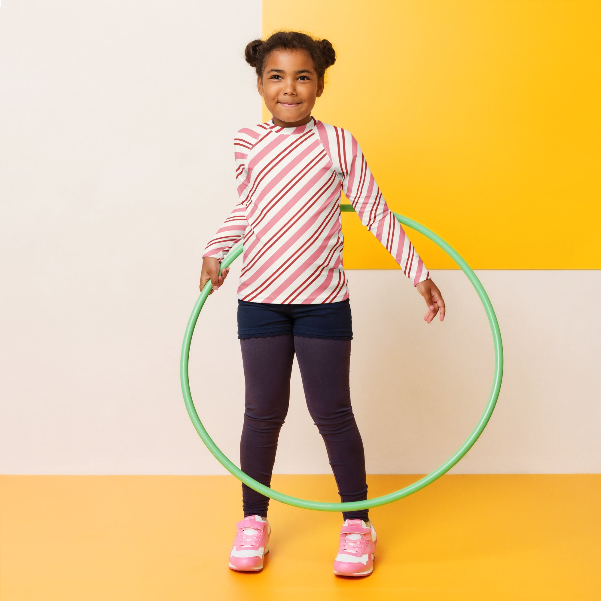 Green plastic hula hoop paired with kids pink peppermint stripe long sleeve rash guard swim shirt with upf 50+
