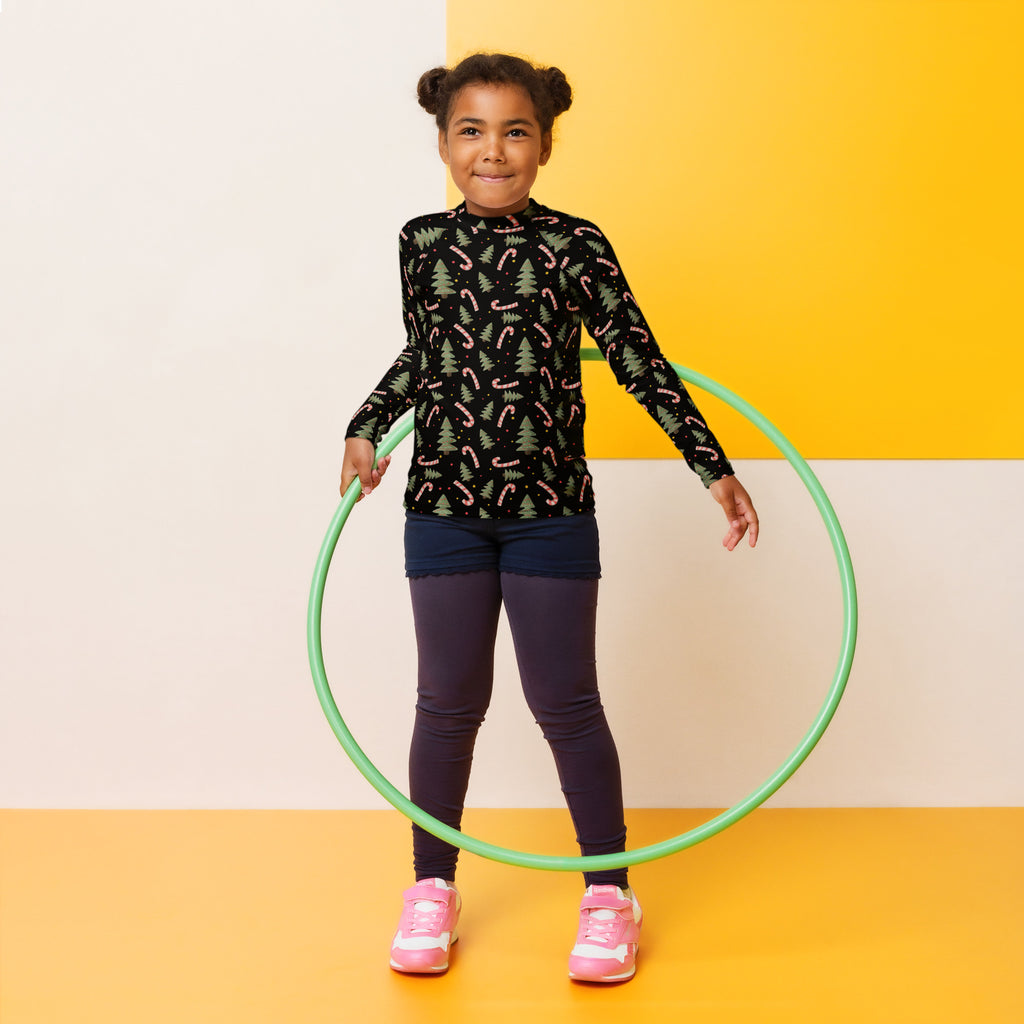 Green plastic hula hoop alongside kids candy cane and christmas tree long sleeve rash guard swim shirt with upf 50+