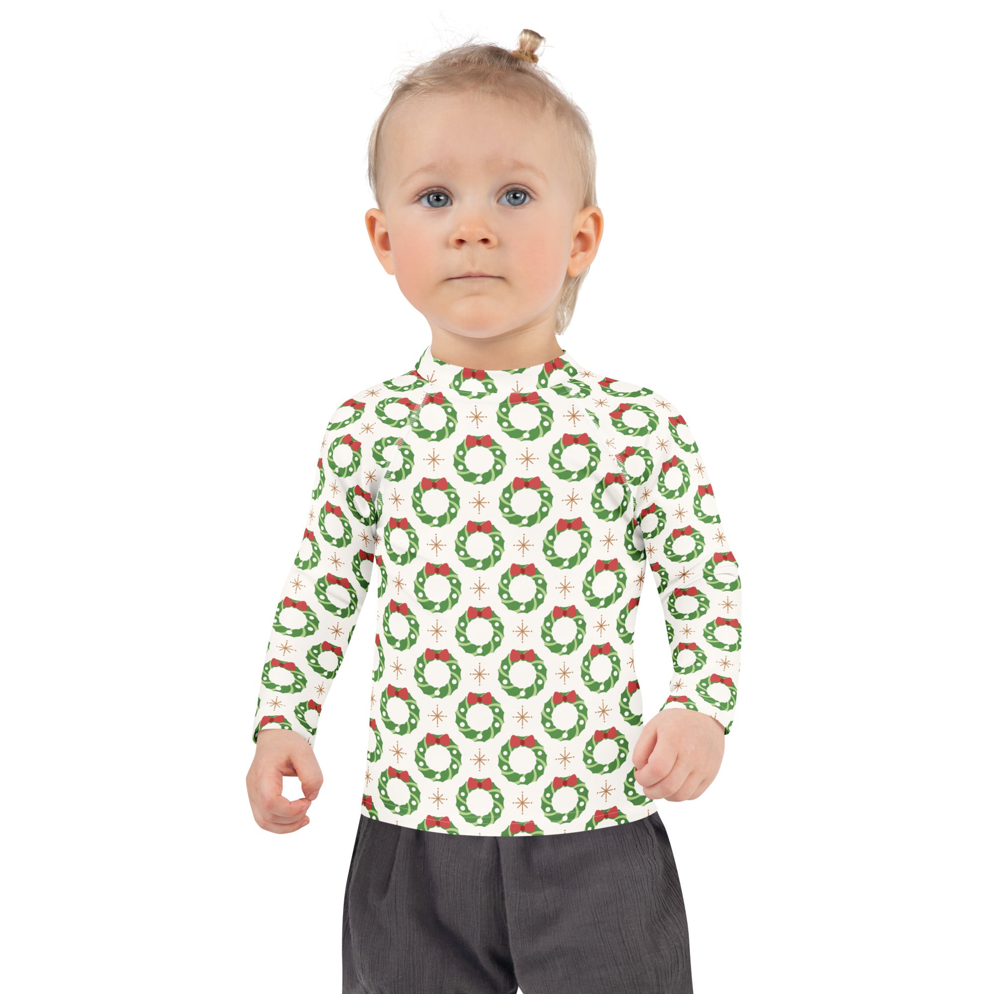 A child wearing a white kids christmas wreath long sleeve rash guard swim shirt with green wreaths and red bows and upf 50+