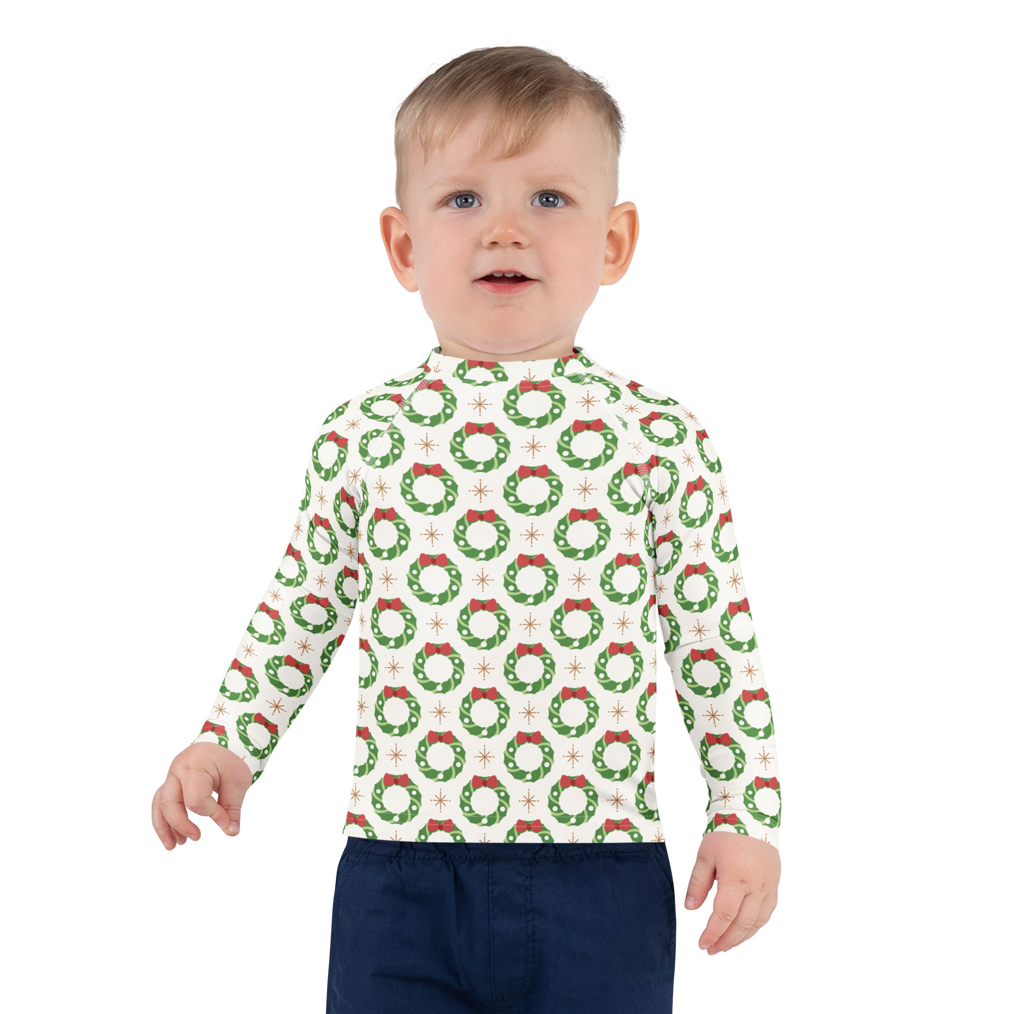 A child wearing a white kids christmas wreath long sleeve rash guard swim shirt with upf 50 plus and green wreaths