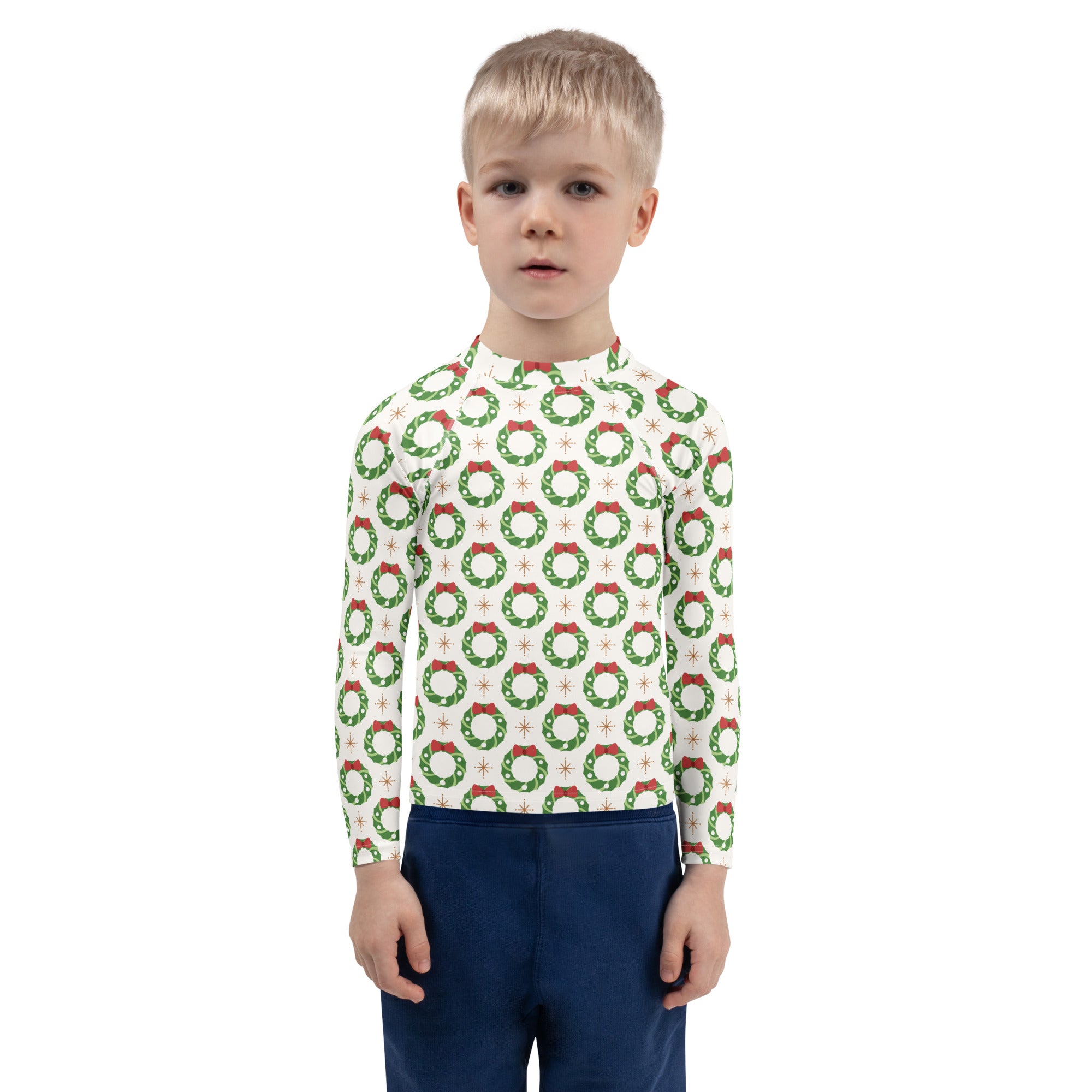 A child wearing a white kids christmas wreath long sleeve rash guard swim shirt with upf 50 plus and green wreaths