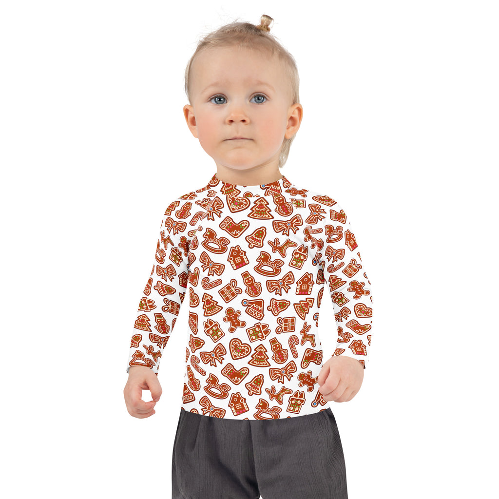 A child wearing a white kids gingerbread cookie long sleeve rash guard swim shirt with upf 50 and orange holiday motifs