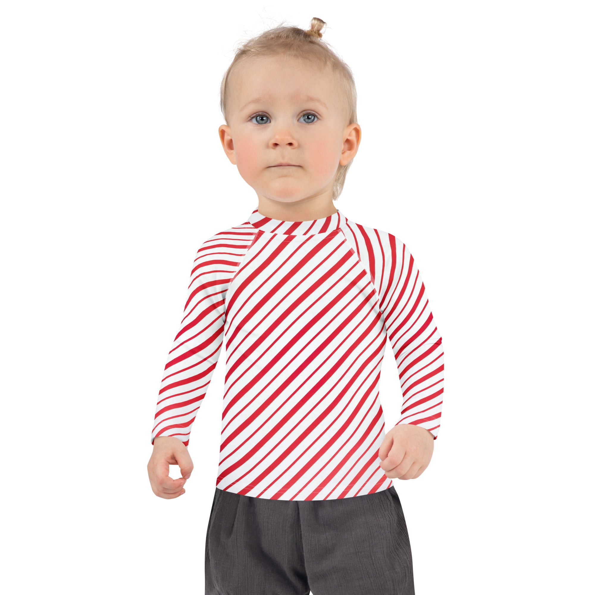 A child wearing a kids red and white candy cane striped long sleeve rash guard swim shirt with UPF 50+ protection