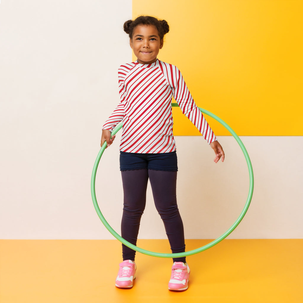 Green plastic hula hoop shown with kids red and white candy cane striped long sleeve rash guard swim shirt with UPF 50+
