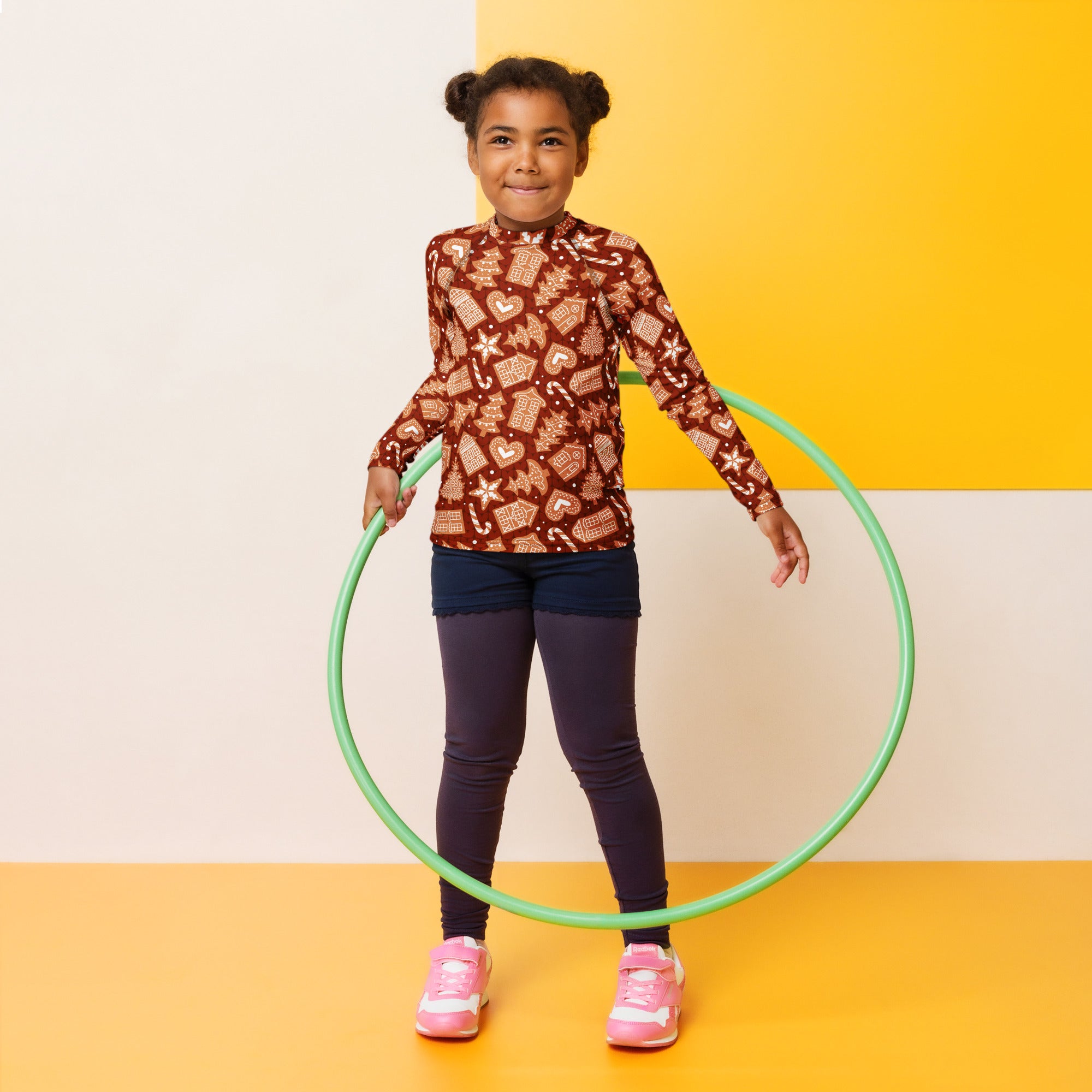 Green plastic hula hoop displayed alongside kids red gingerbread Christmas long sleeve rash guard swim shirt with UPF 50+