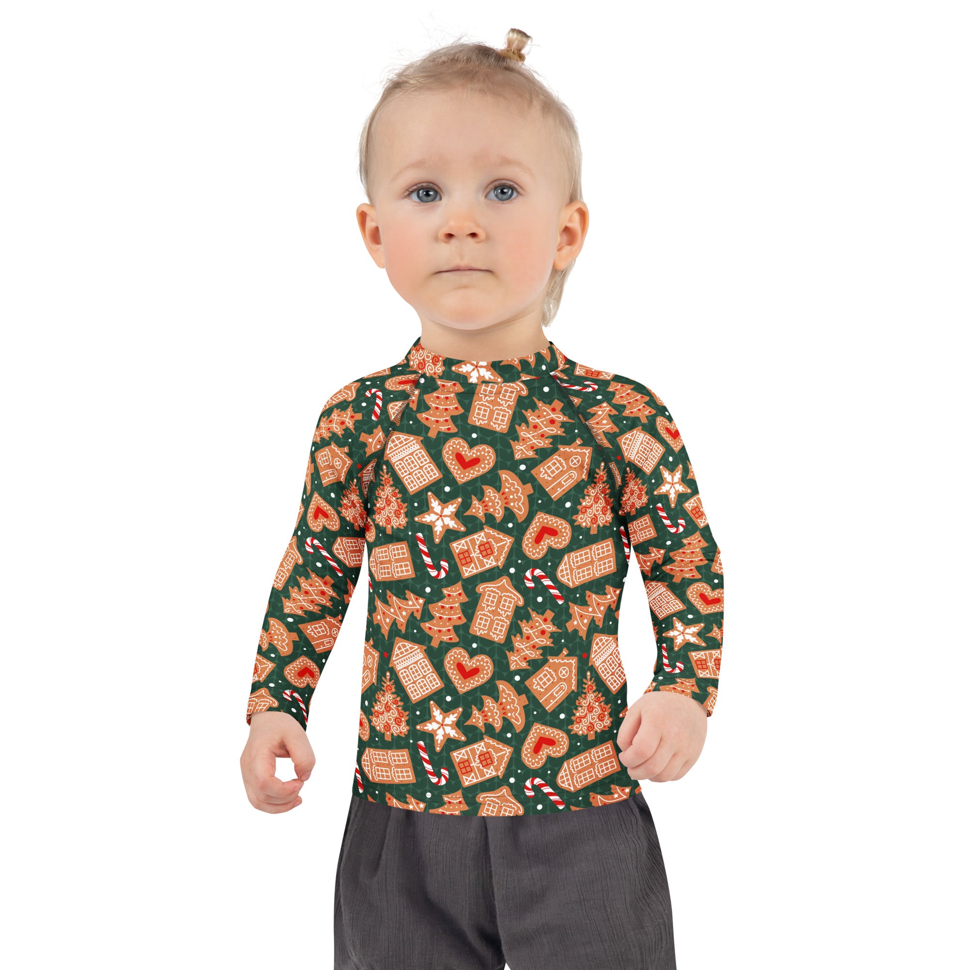 A child wearing a kids green gingerbread christmas long sleeve rash guard swim shirt with upf 50 plus and festive pattern