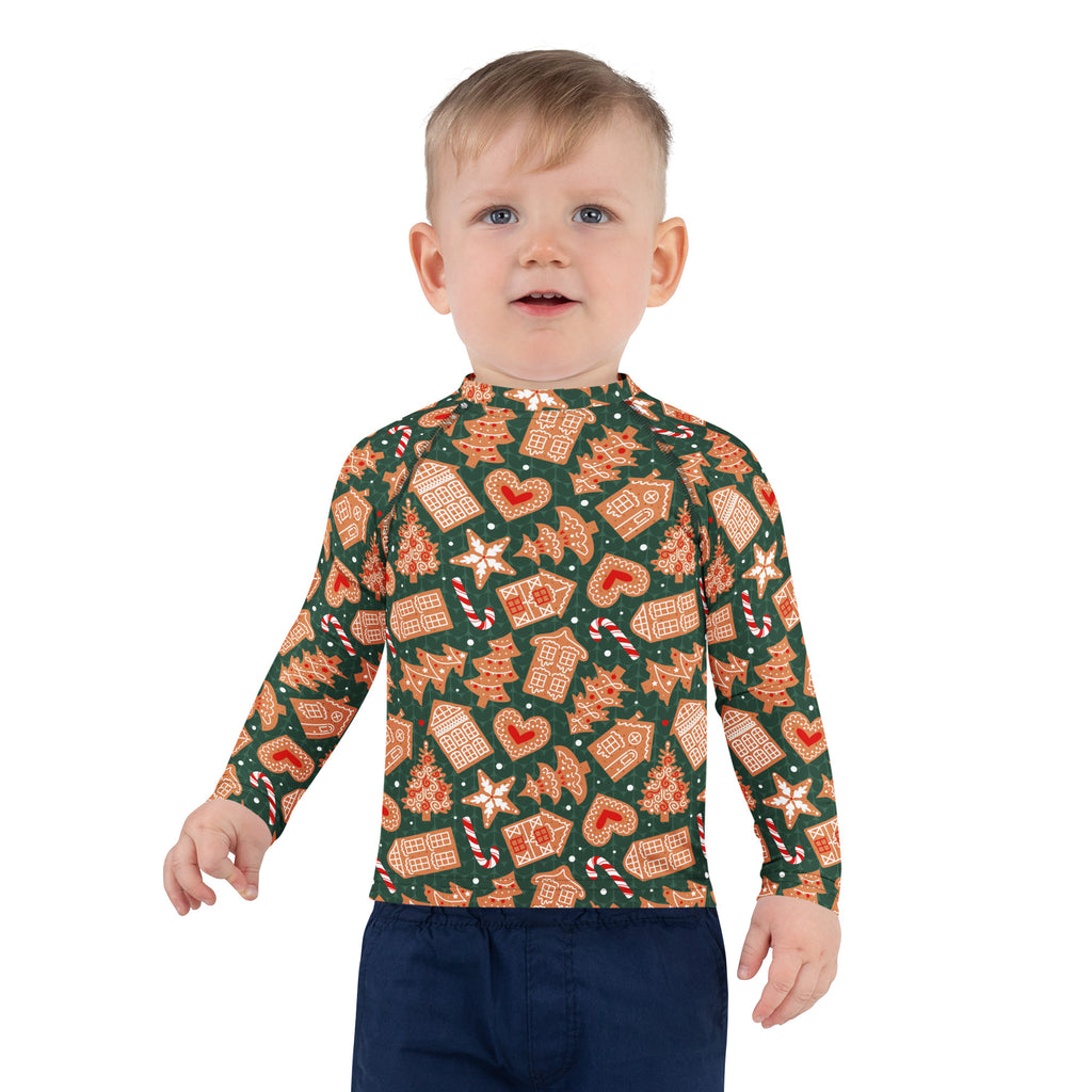 A child wearing a kids green gingerbread christmas long sleeve rash guard swim shirt with upf 50 plus and festive pattern