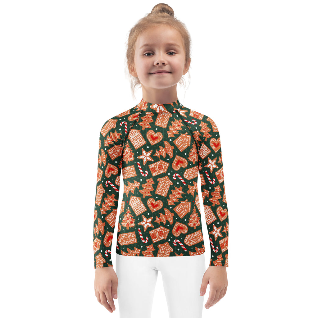 A child wearing a kids green gingerbread christmas long sleeve rash guard swim shirt with upf 50 plus and festive pattern