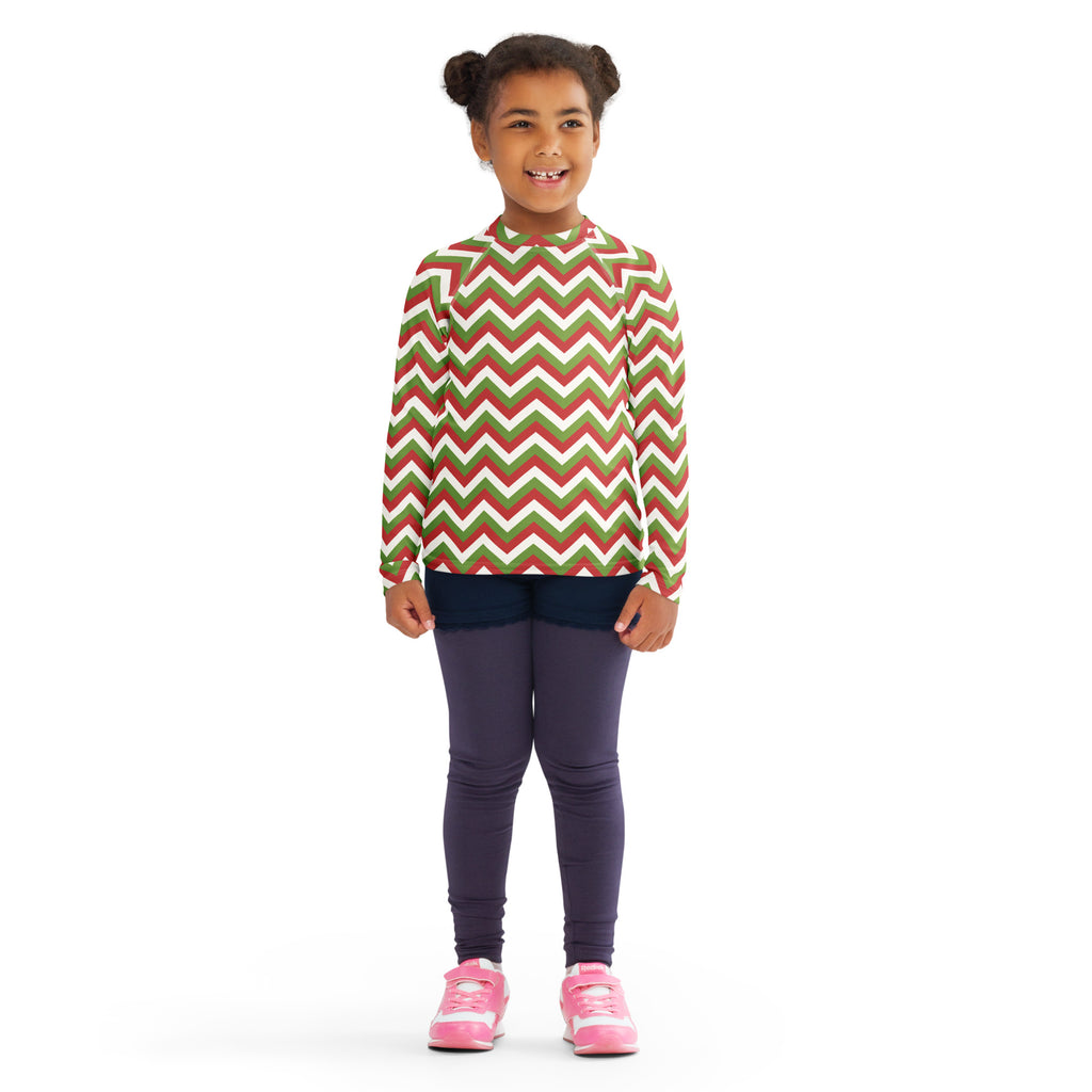 A child wearing a kids red and green chevron christmas long sleeve rash guard swim shirt with UPF 50 plus protection