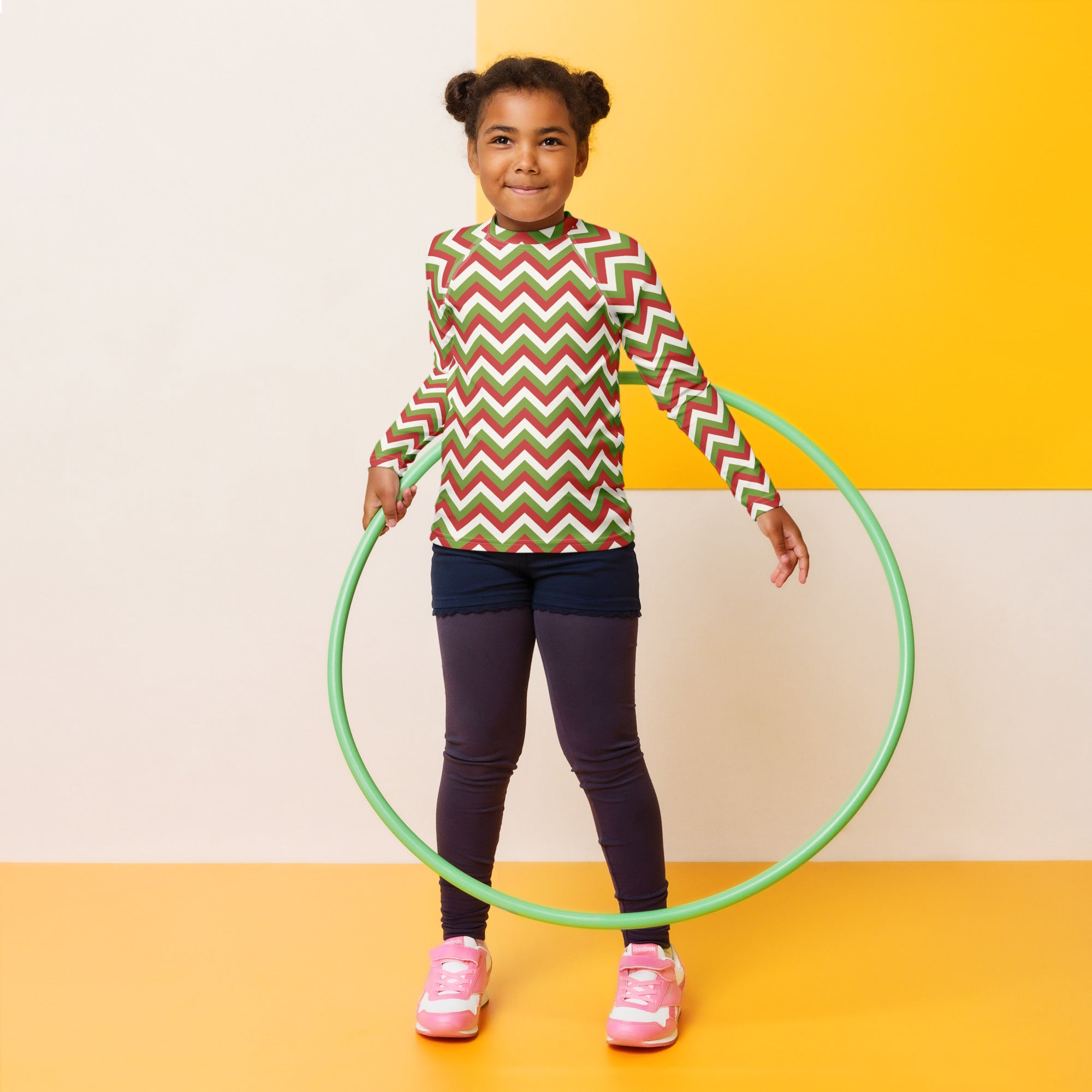 Green plastic hula hoop displayed alongside kids red and green chevron christmas long sleeve rash guard swim shirt with upf 50+