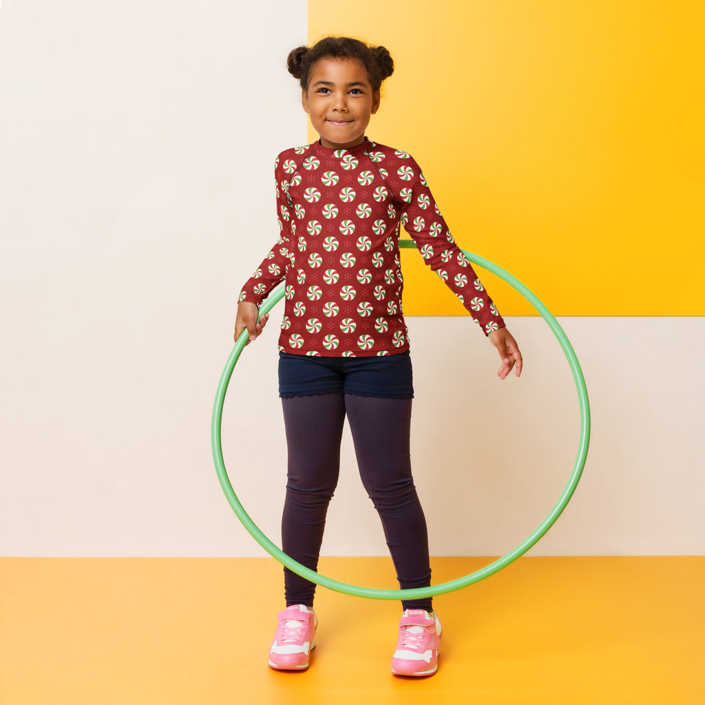 Green plastic hula hoop shown with kids peppermint swirl christmas long sleeve rash guard swim shirt with upf 50+