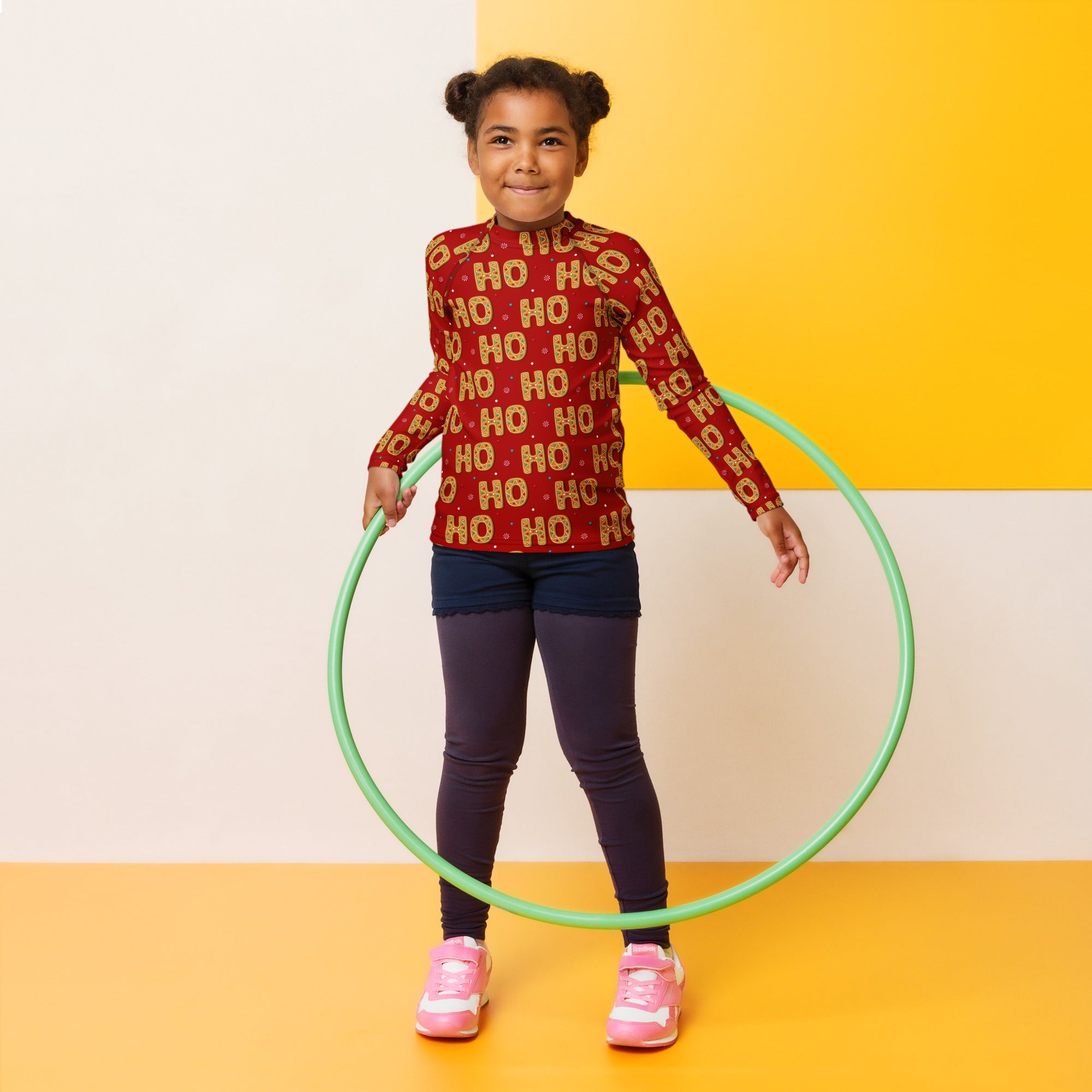 Green plastic hula hoop shown with kids ho ho ho gingerbread christmas long sleeve rash guard swim shirt with upf 50+