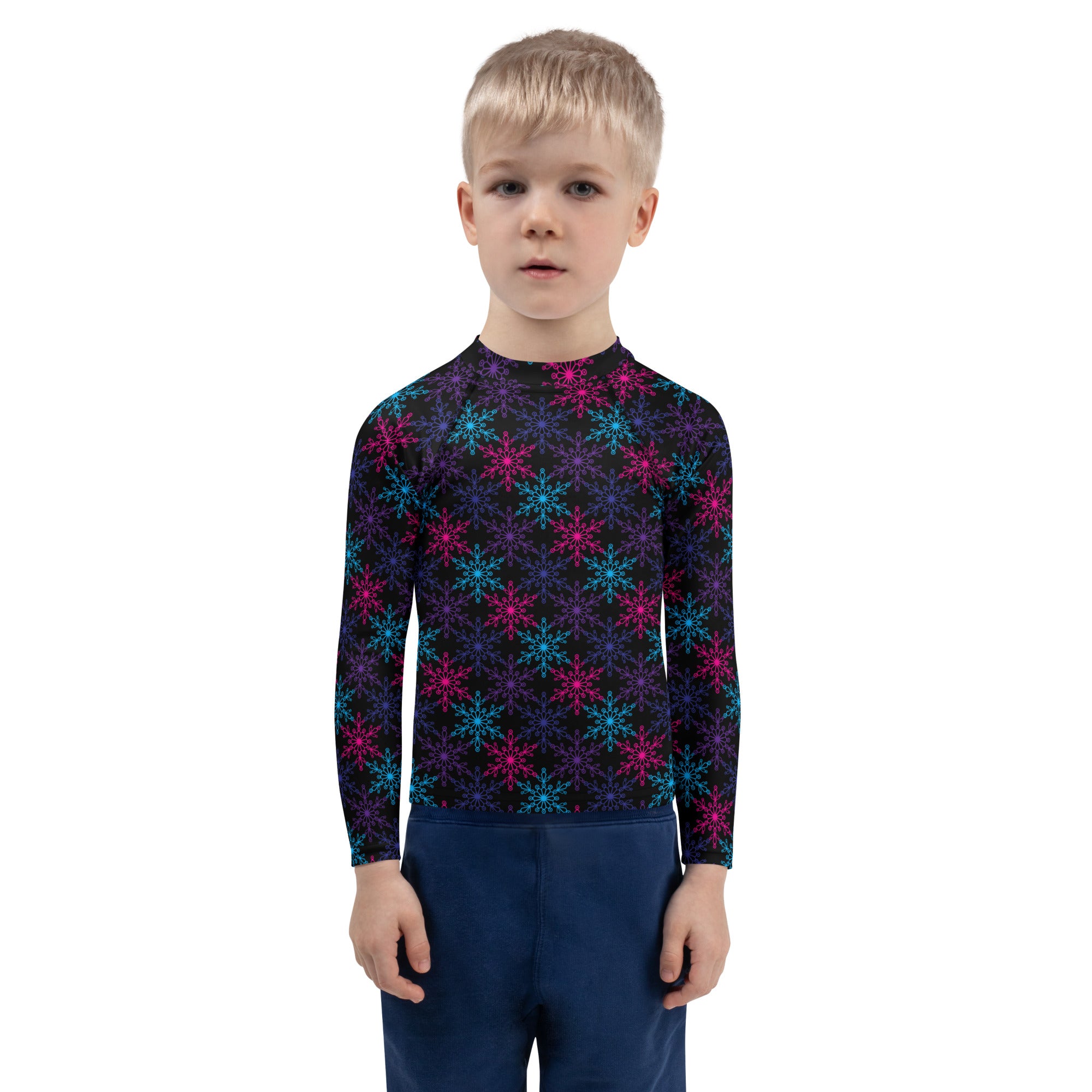 A child wearing a black long sleeve kids neon snowflakes rash guard swim shirt with pink and teal snowflake patterns and UPF 50+