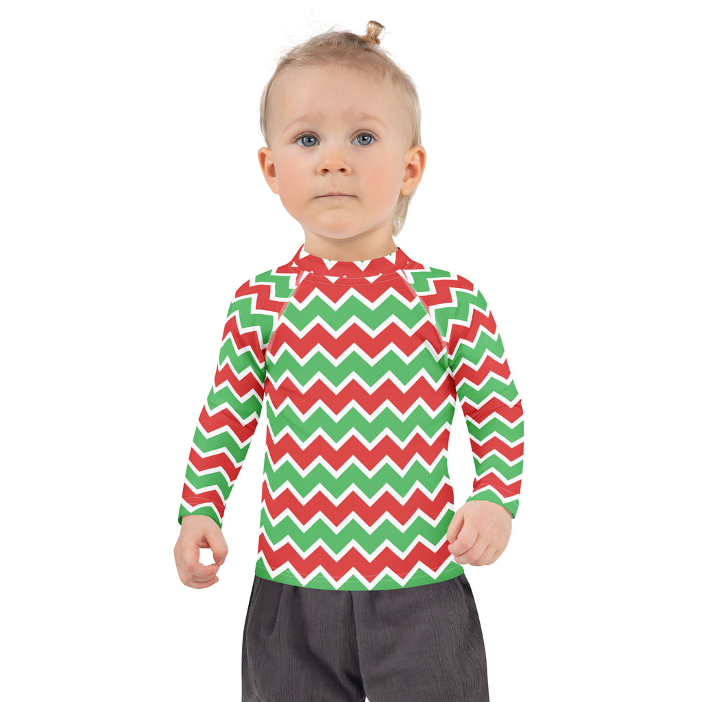 A child wearing a kids christmas chevron long sleeve rash guard swim shirt with upf 50 plus in red and green zigzag pattern