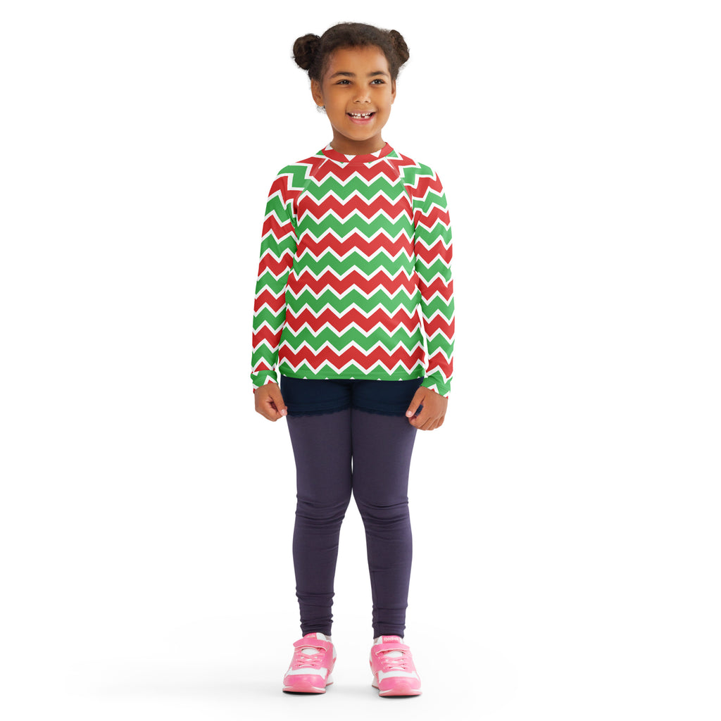A child wearing a kids christmas chevron long sleeve rash guard swim shirt with red green zigzag pattern and UPF 50+