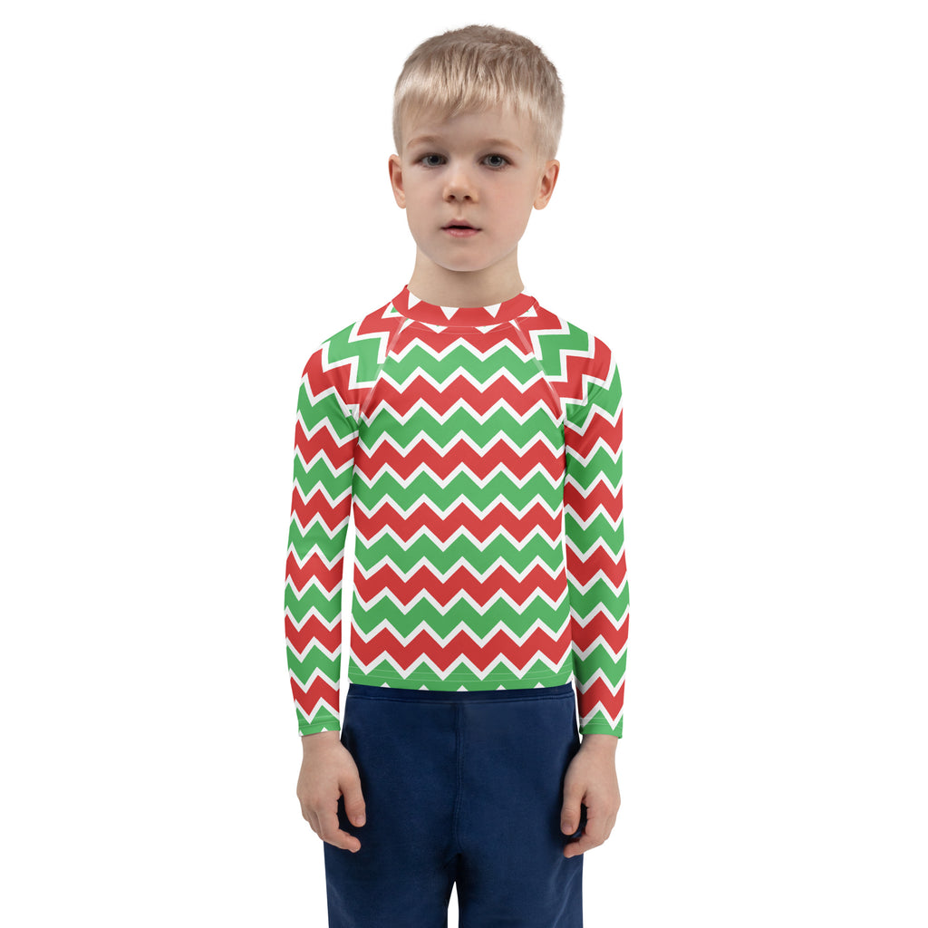 A child wearing a kids Christmas chevron long sleeve rash guard swim shirt with UPF 50 plus in red green and white