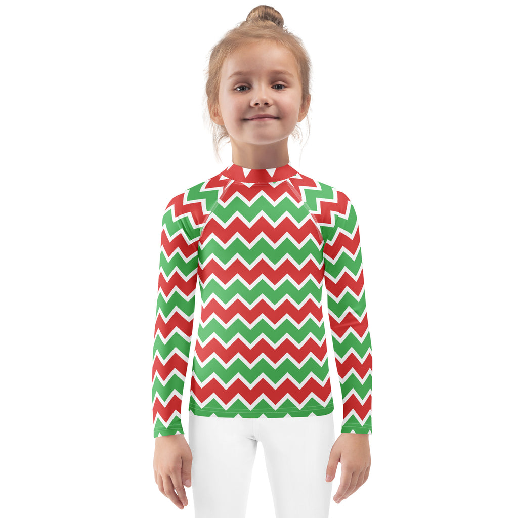 A child wearing a kids christmas chevron long sleeve rash guard swim shirt with vibrant red and green zigzag pattern and UPF 50+ protection
