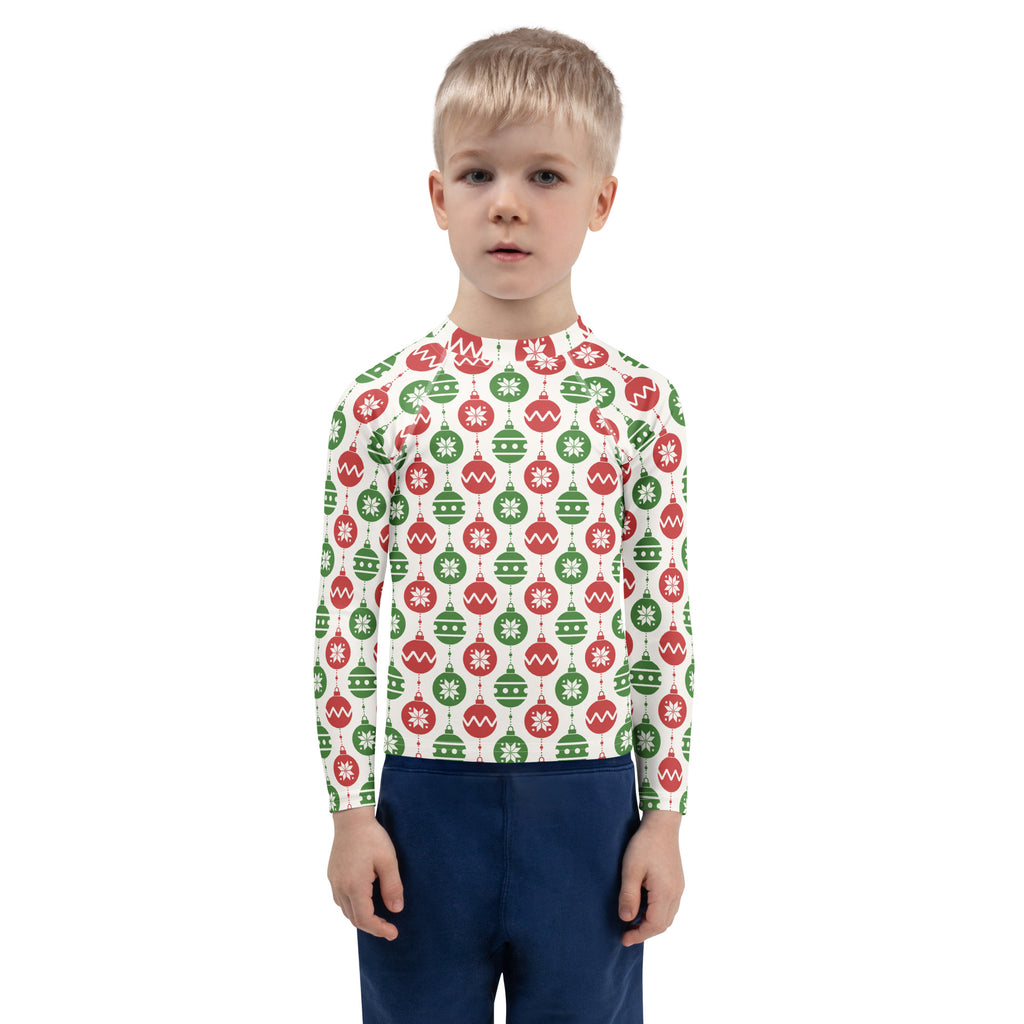 A child wearing a white long sleeve kids rash guard with red and green christmas ornament patterns and UPF 50+ protection