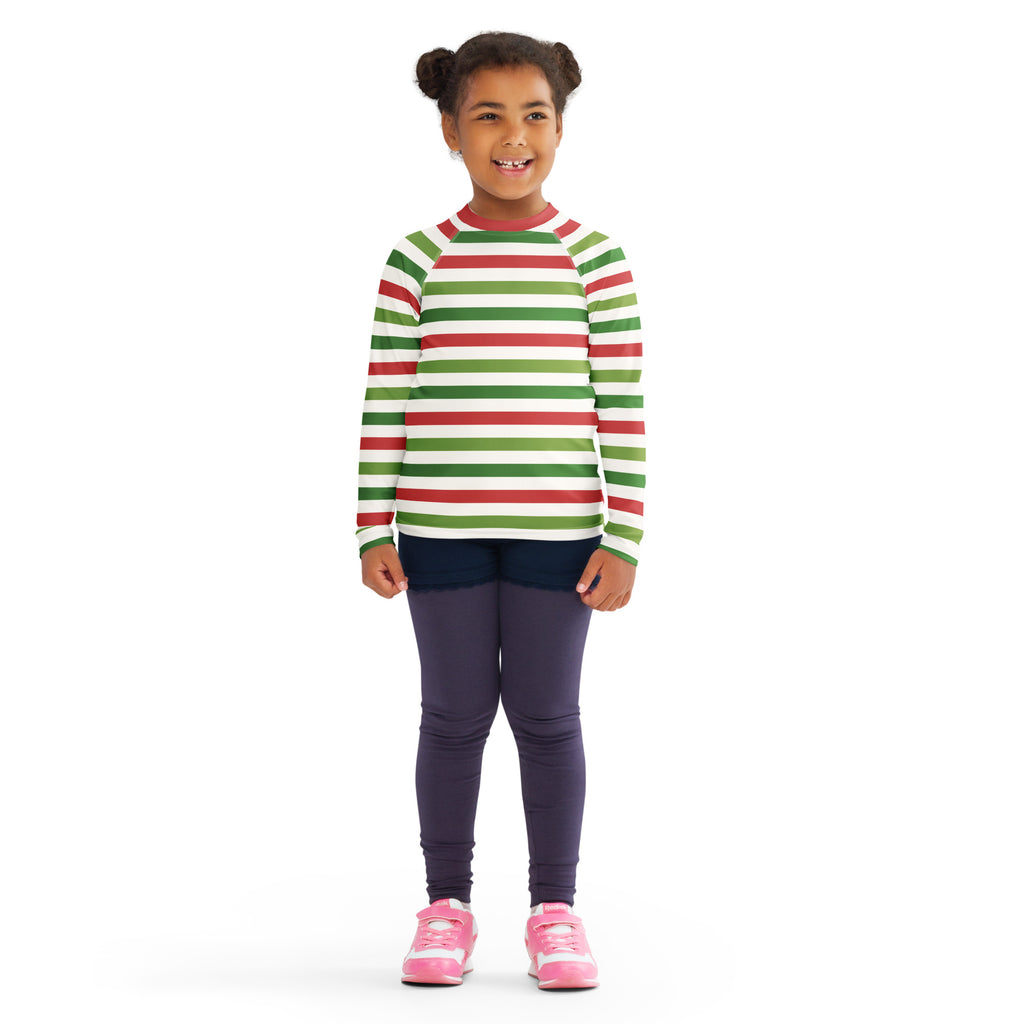 A child wearing a kids red and green christmas stripes long sleeve rash guard swim shirt with upf 50 plus