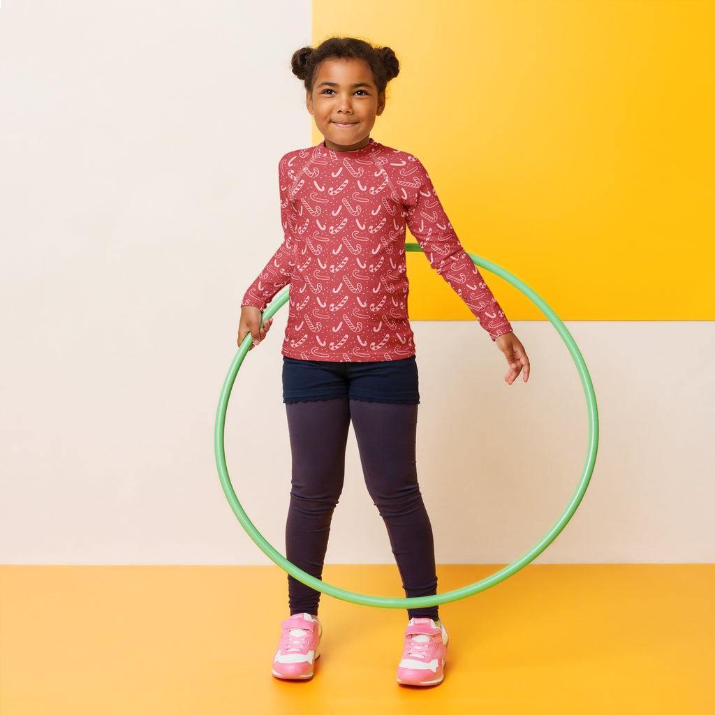 Kids red candy cane Christmas long sleeve rash guard swim shirt with upf 50 plus shown with a green plastic hula hoop