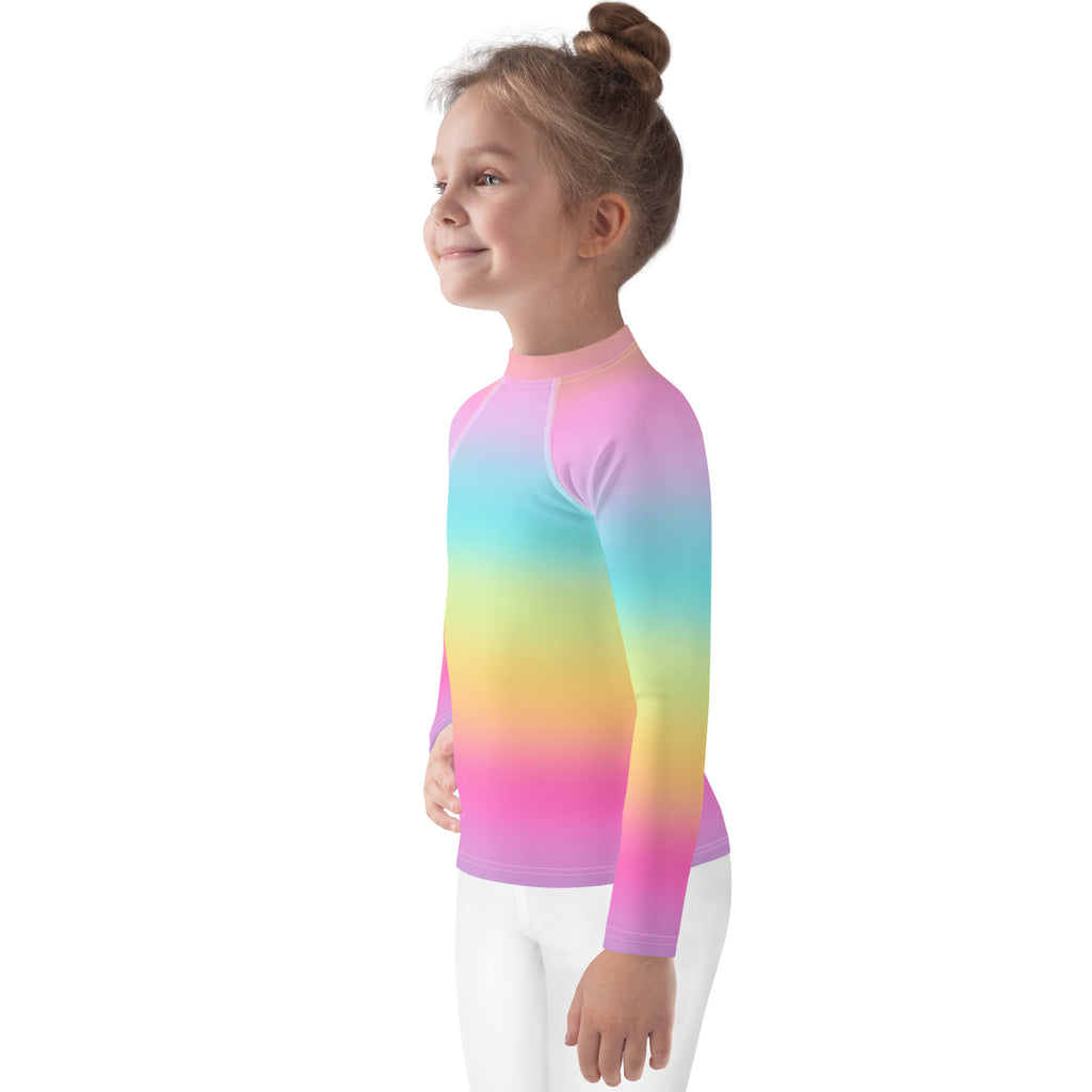 A child wearing a girls bright rainbow long sleeve rash guard swim shirt with upf 50 plus smooth stretchy fabric