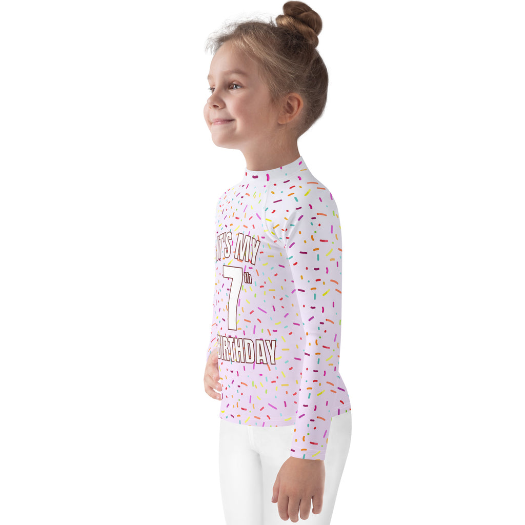 White long-sleeved rash guard with colorful sprinkles and bold it’s my 7th birthday text with upf 50+ protection