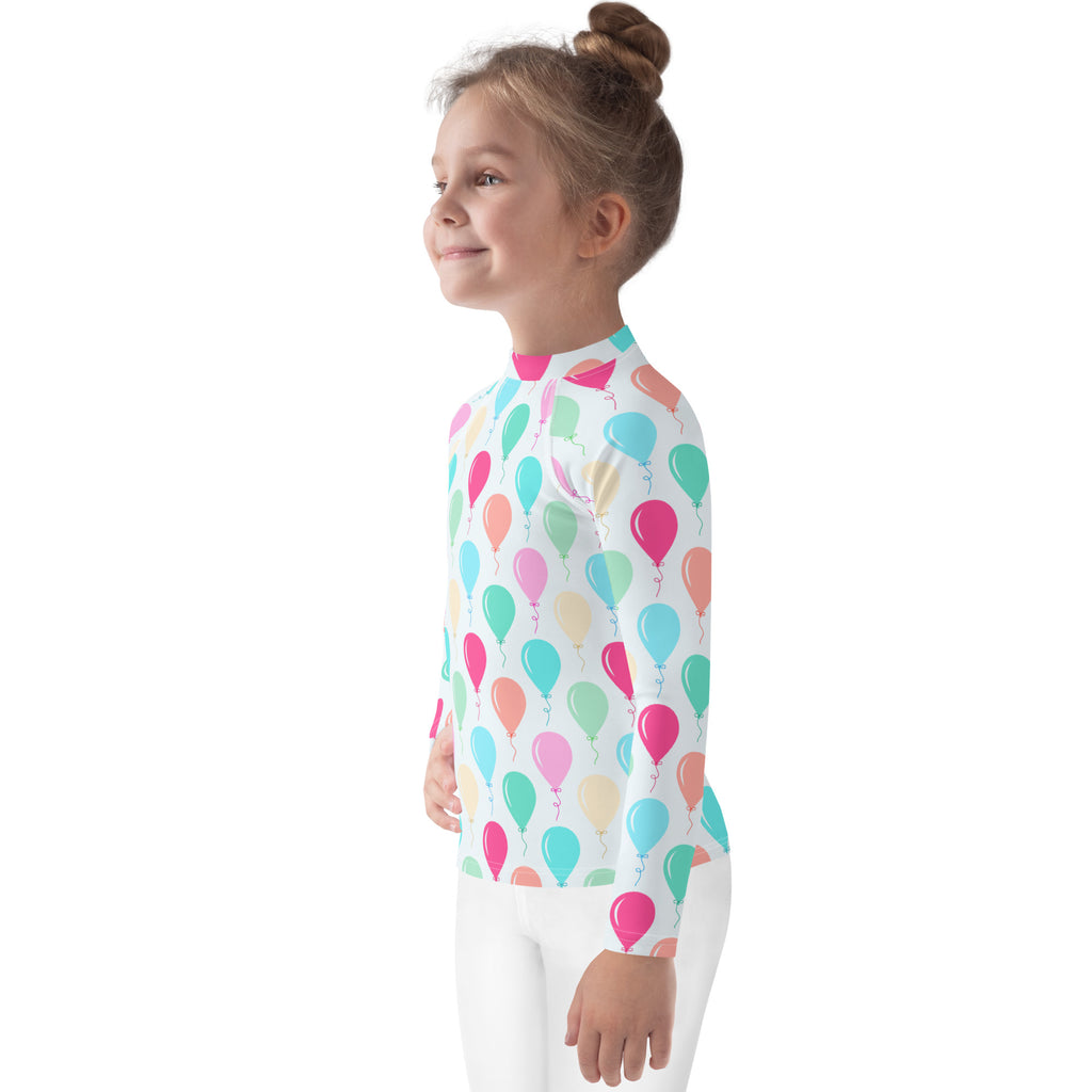 A child wearing a kids birthday balloons long sleeve rash guard swim shirt with UPF 50 plus and pastel balloon pattern