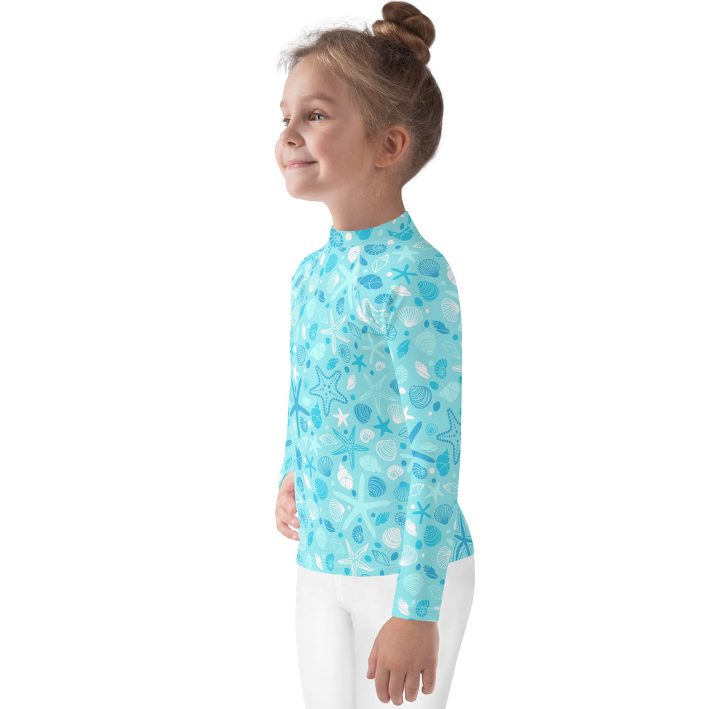 A light blue kids long-sleeve rash guard with seashell and starfish pattern and UPF 50 plus sun protection